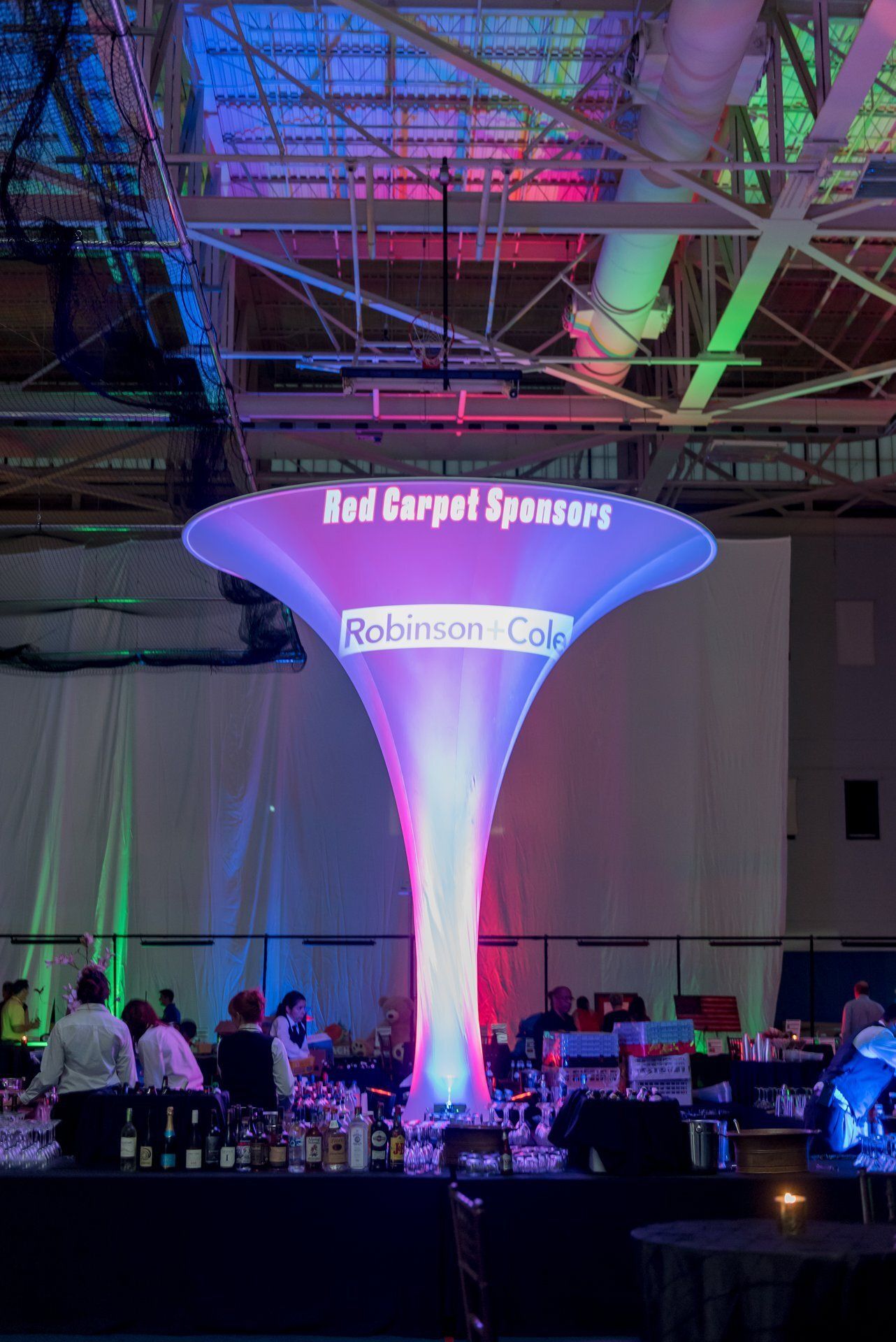 Illuminated event table centerpiece with red and blue lights at a busy indoor networking reception