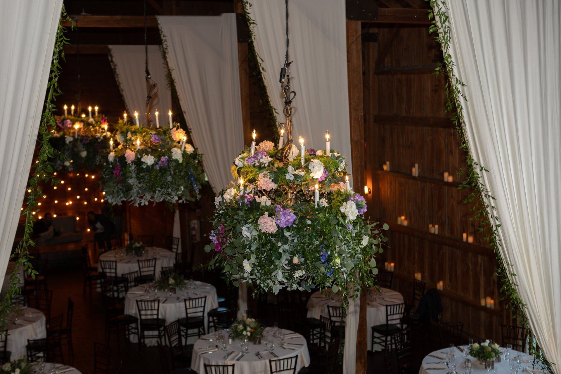 Elegant indoor dining area with hanging flower baskets, warm lights, and draped curtains