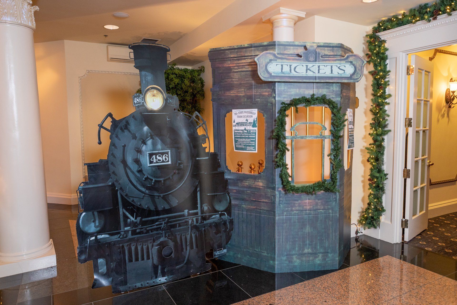 Vintage train display with black locomotive and red brick ticket booth in an indoor lobby