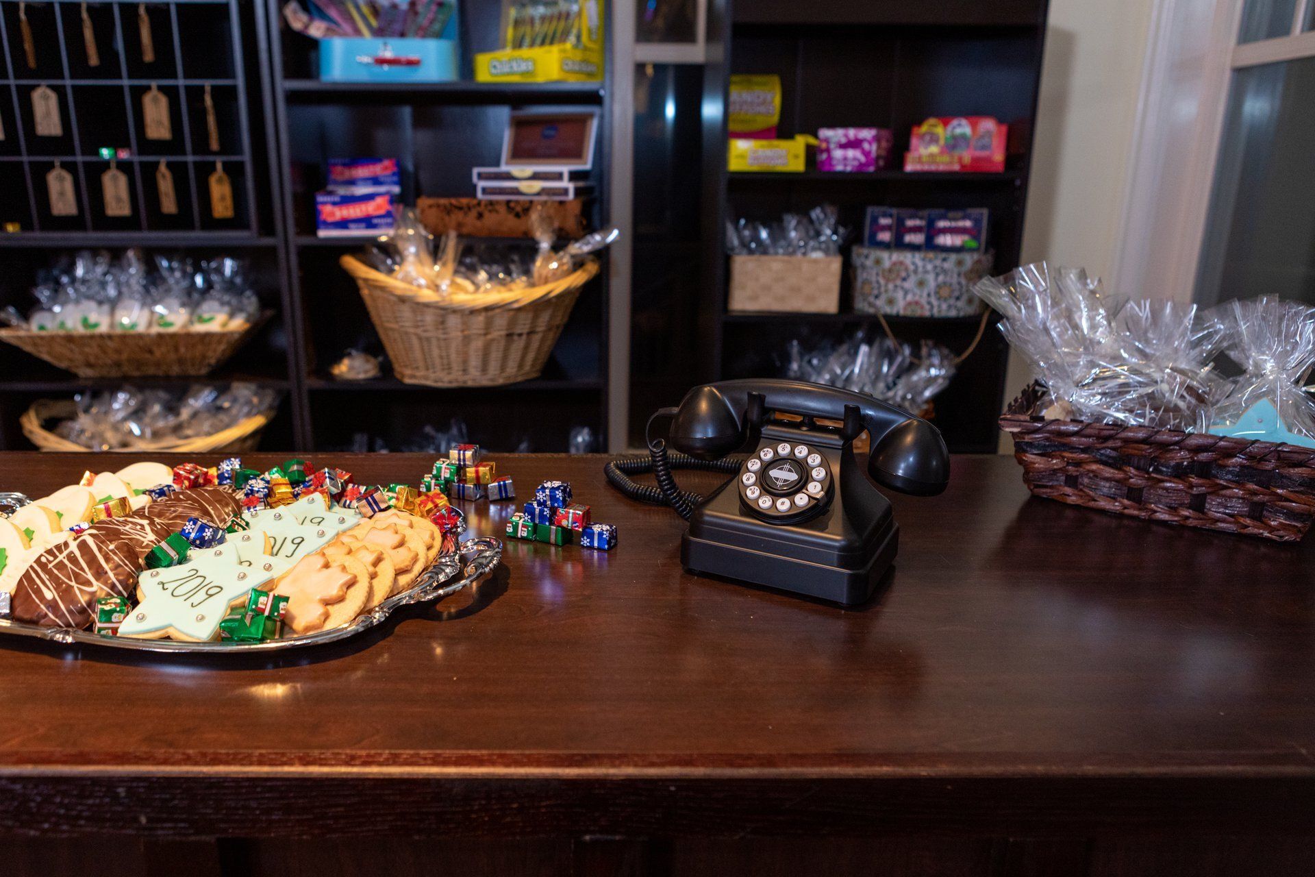 Candy and snack display on a dark wooden counter with a vintage black rotary phone.
