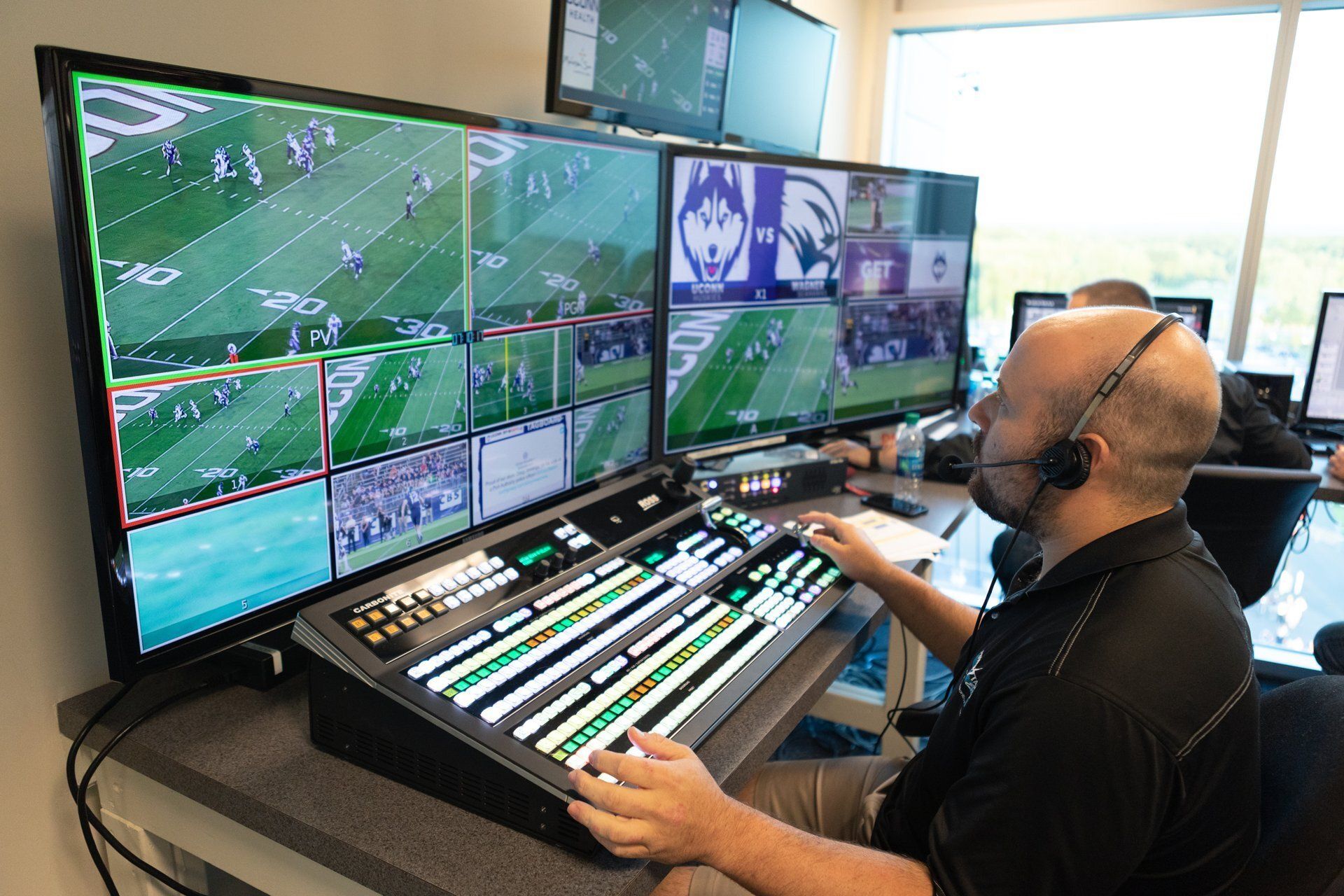 Sports video control room with multiple monitors and an operator at a broadcast console