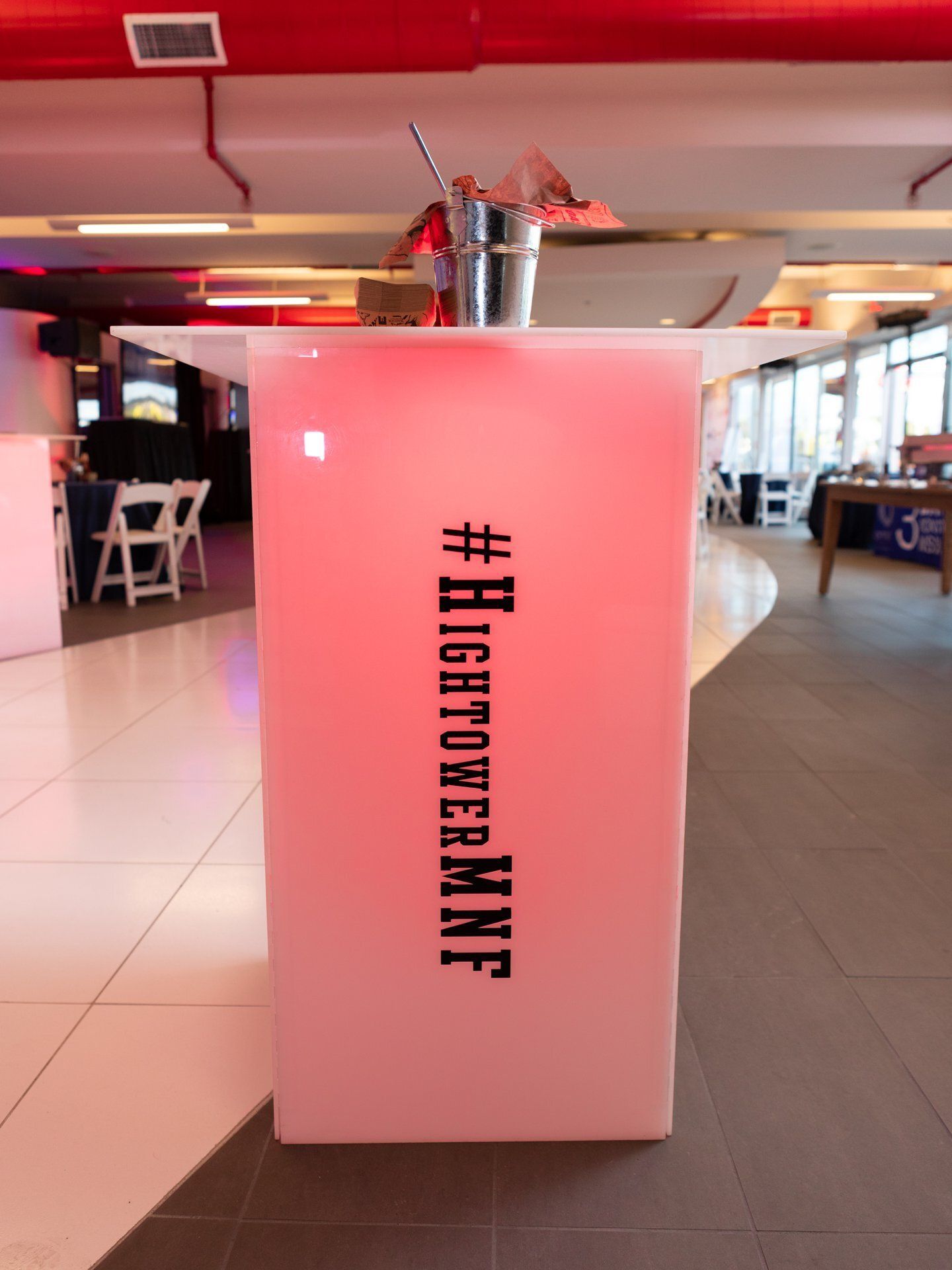 Pink display stand with vertical black text in a brightly lit indoor lounge or café area