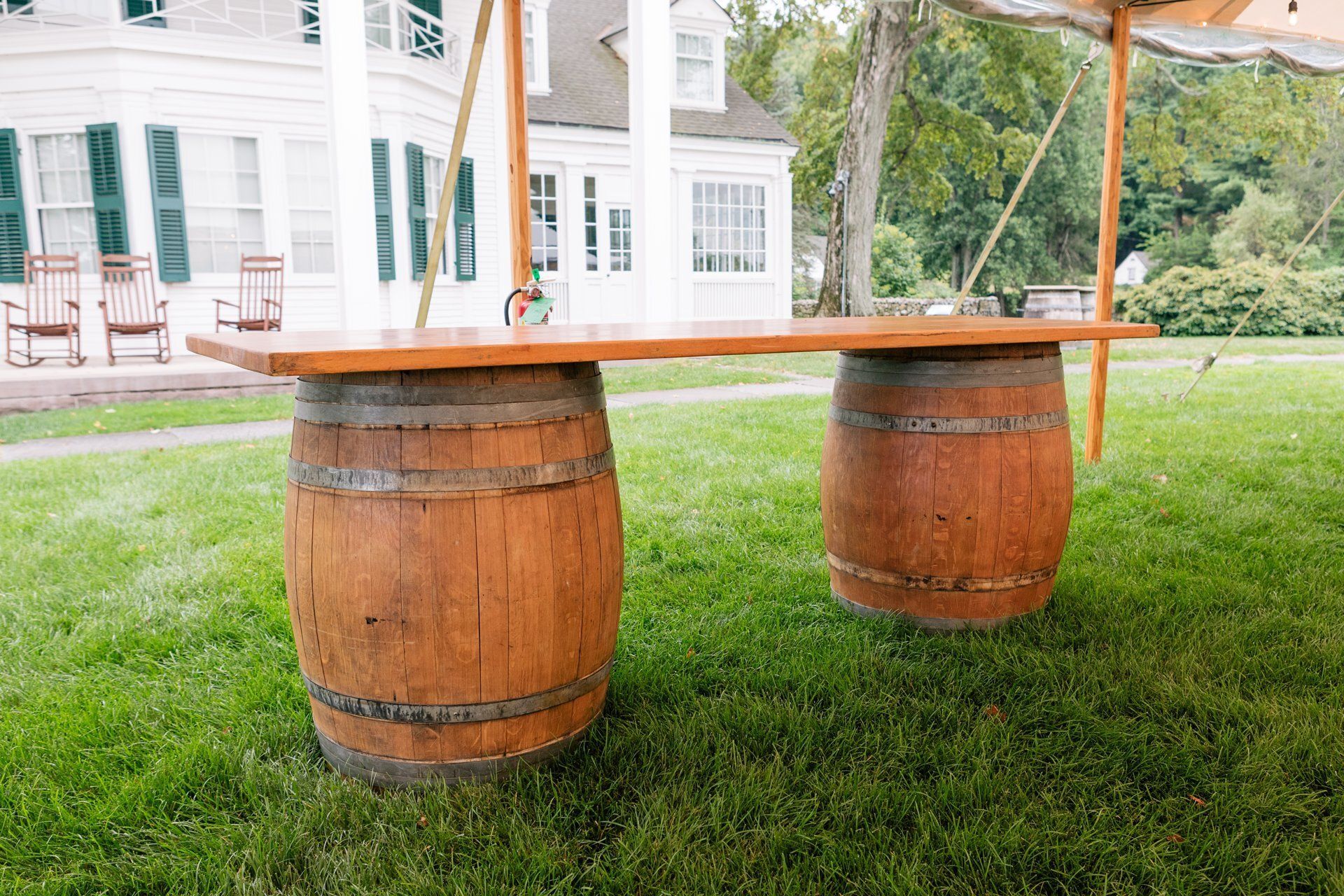 Wooden bench made from two barrels on a grassy lawn beside a white house