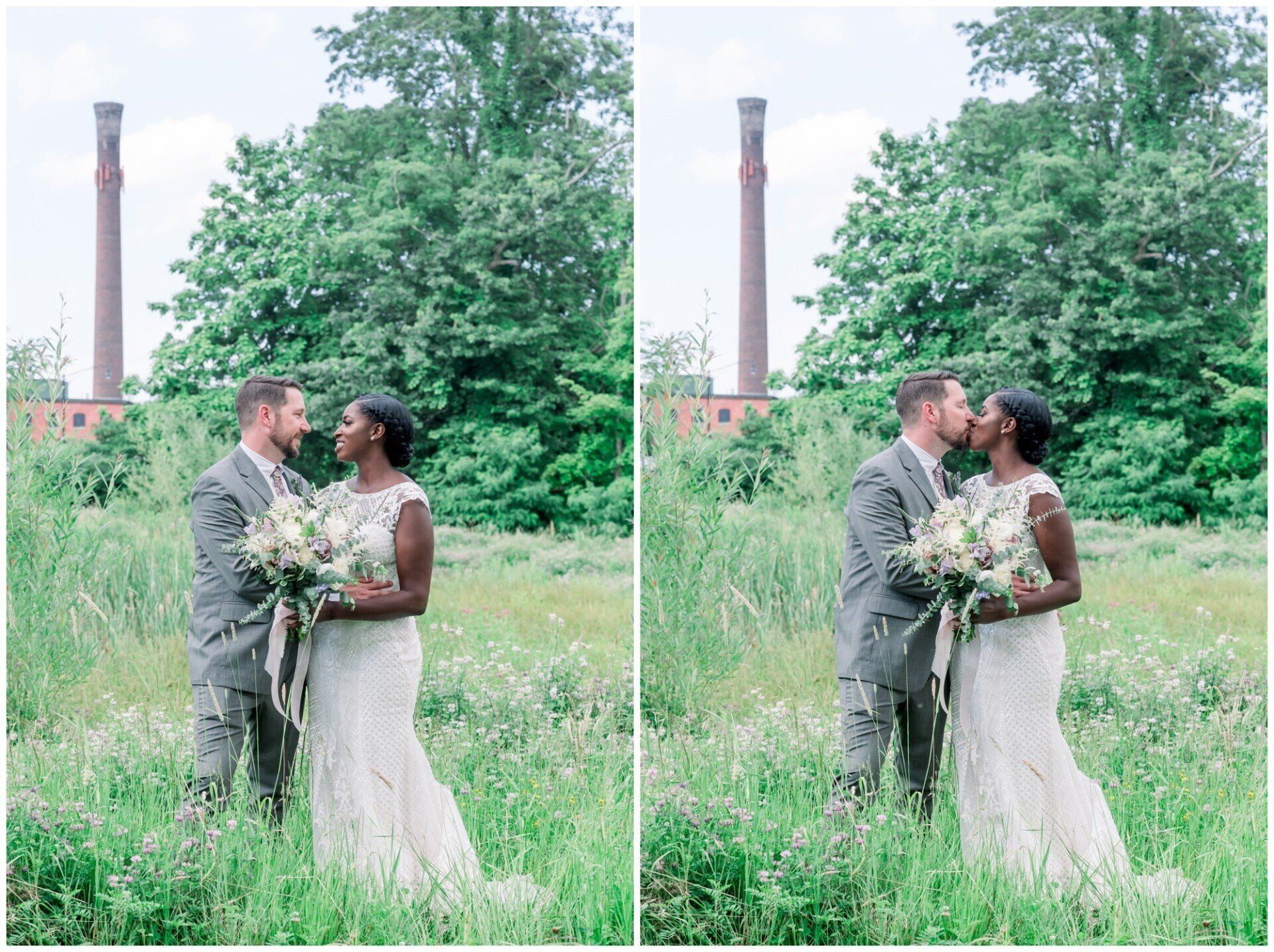 Couple in wedding attire kissing in a grassy field, with trees and a smokestack in the background.