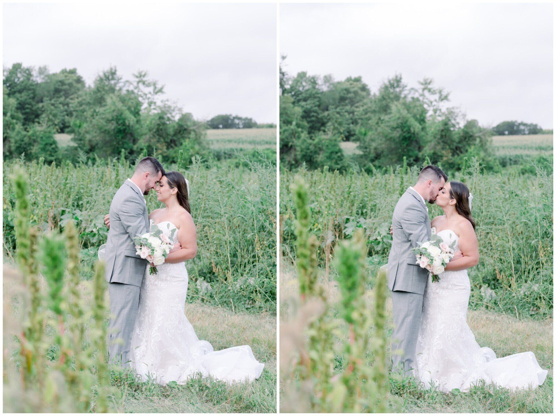 Couple in wedding attire embracing in a grassy field, with trees and overcast sky behind them.