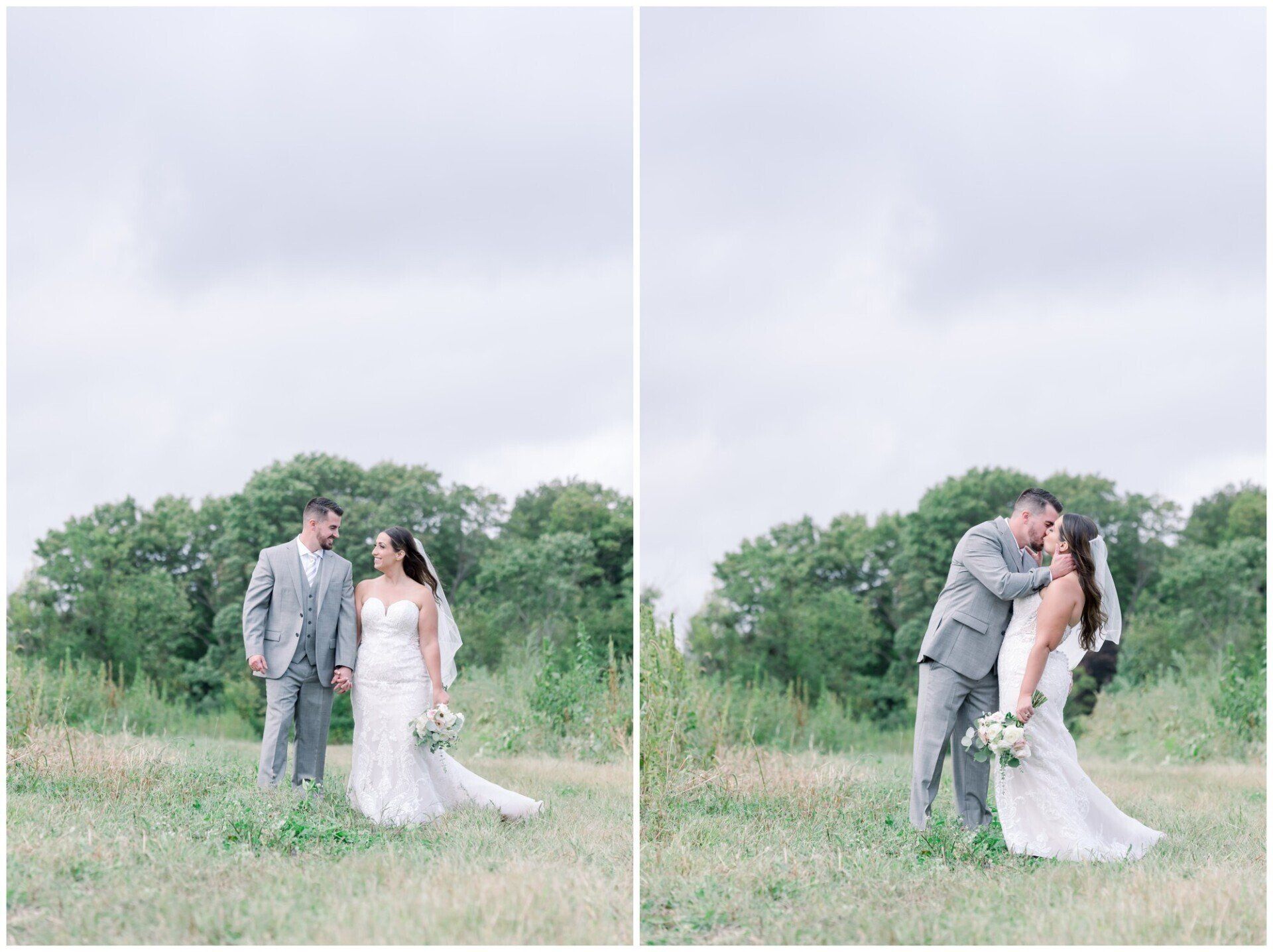 Couple in gray and white wedding attire posing and kissing in a grassy field under cloudy skies