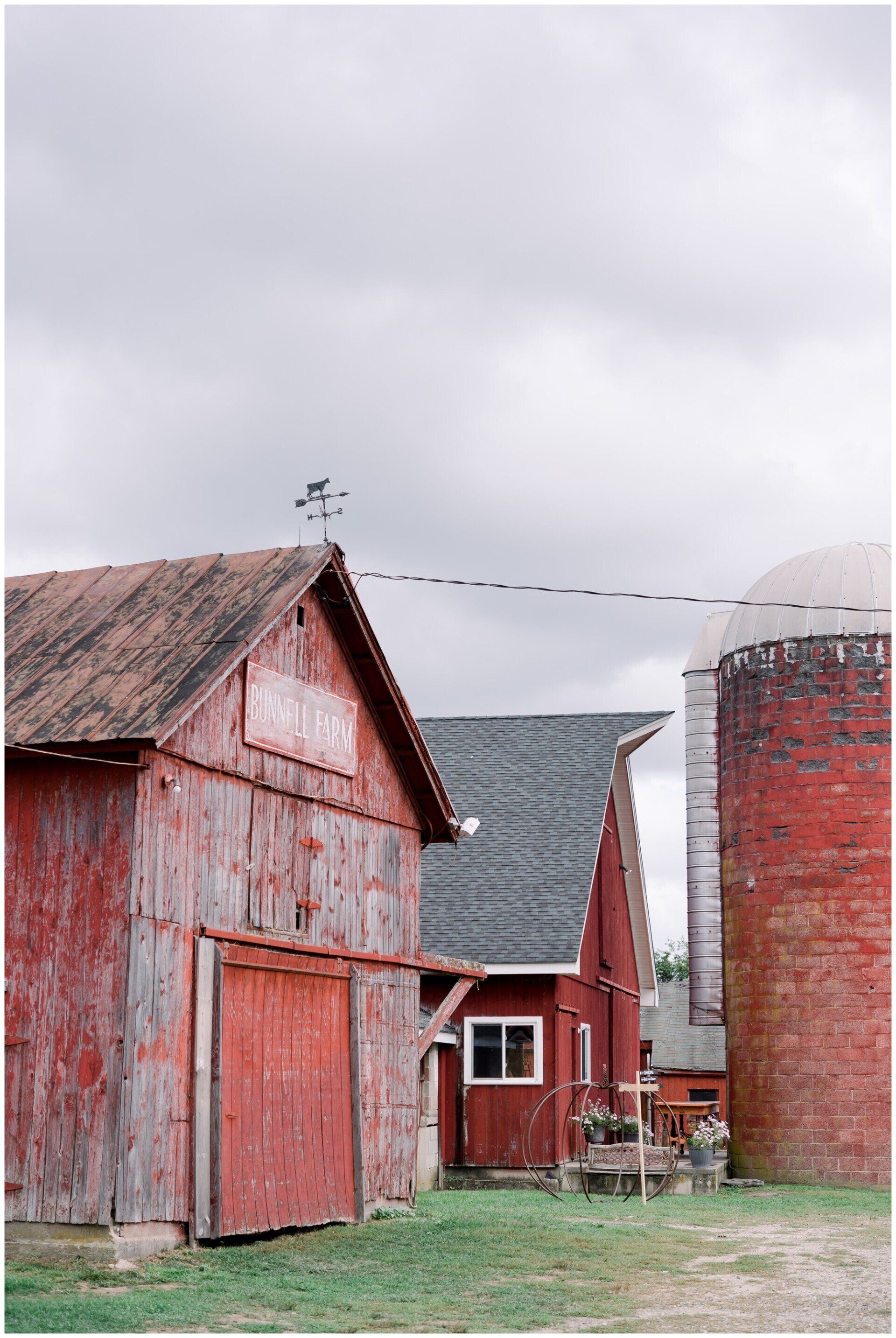 Weathered red barn and silo on a farm under a cloudy sky