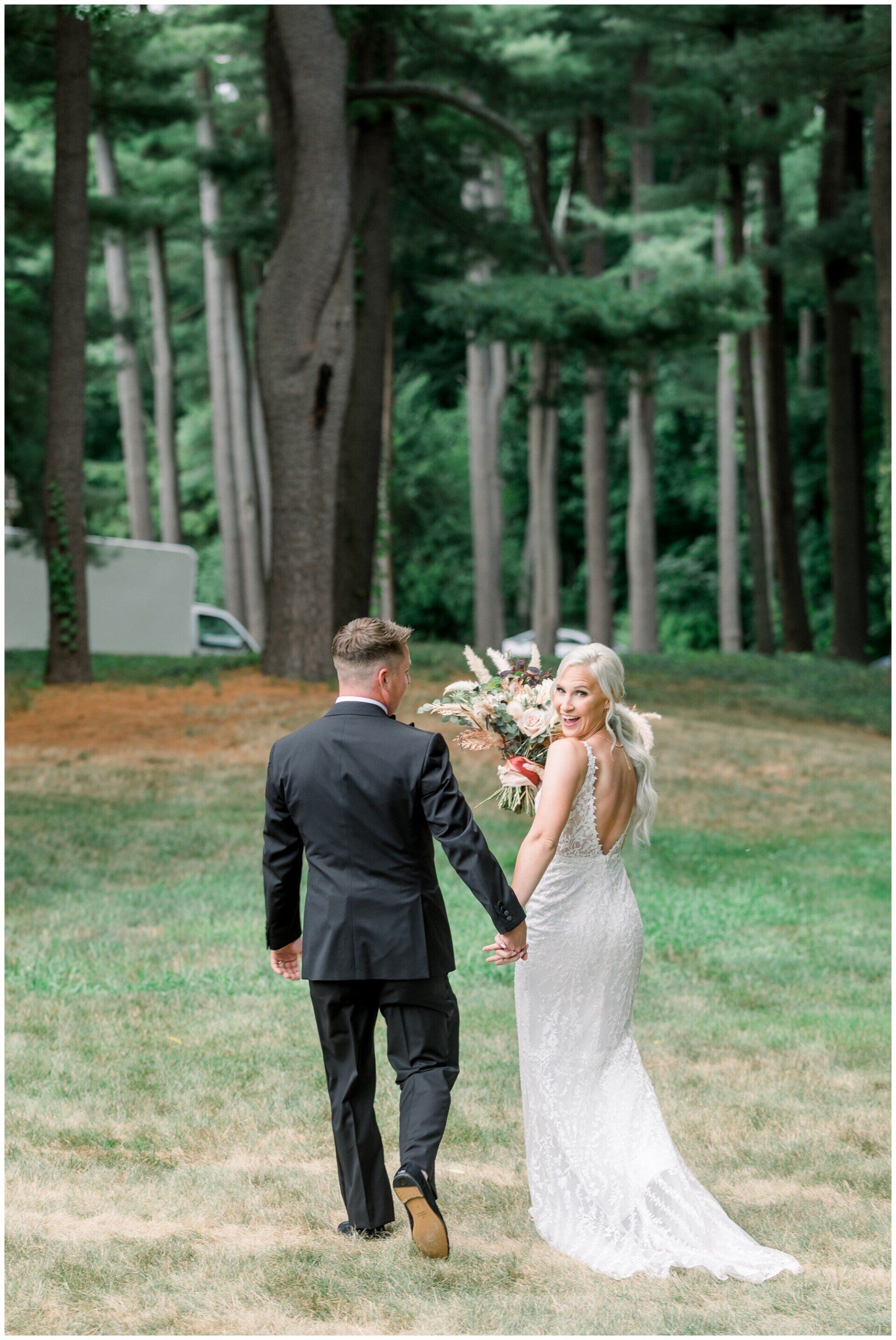 Couple in formal wear holding hands and walking through a wooded park