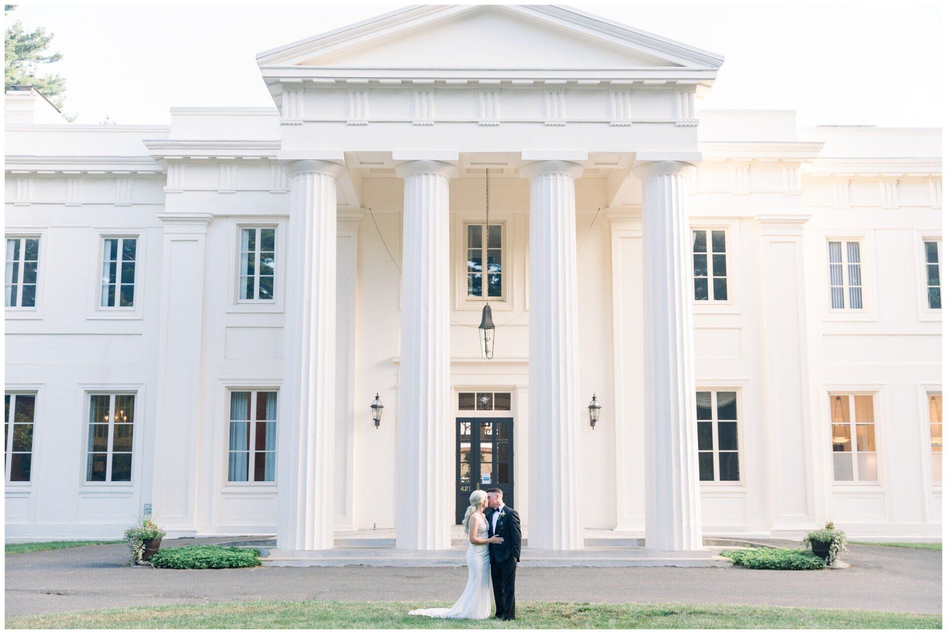 Couple in wedding attire standing outside a grand white neoclassical building