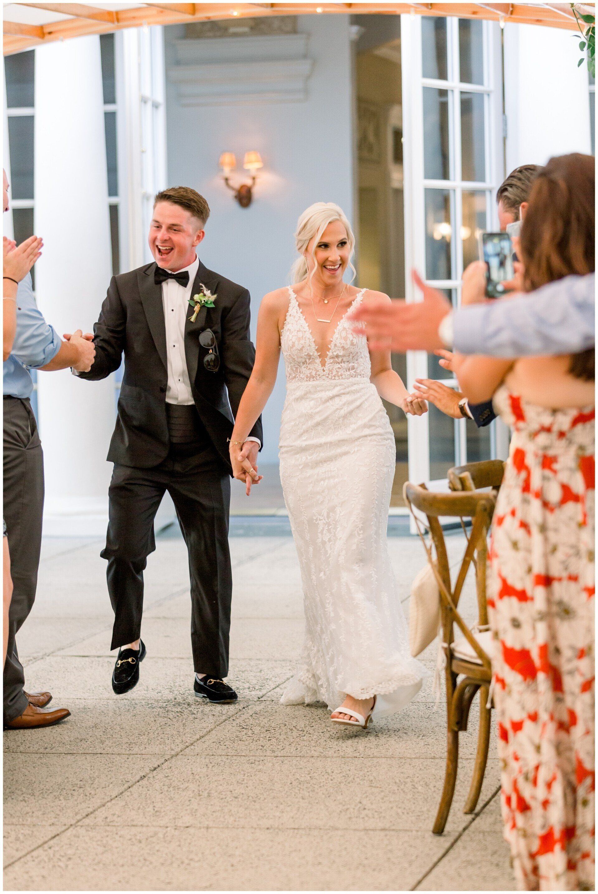 Bride and groom holding hands and dancing at an outdoor wedding reception under a lighted canopy