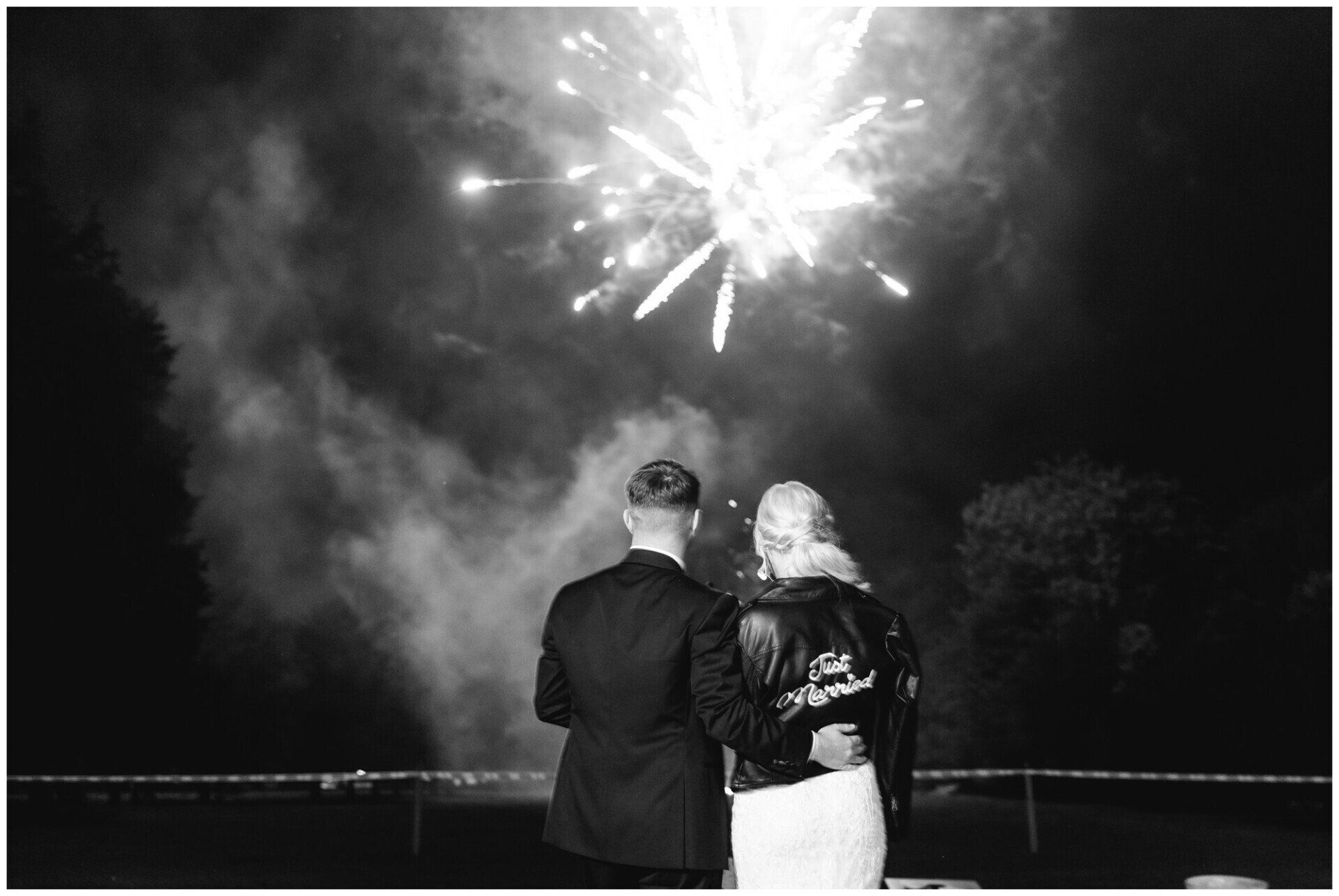 Couple standing by water watching fireworks at night