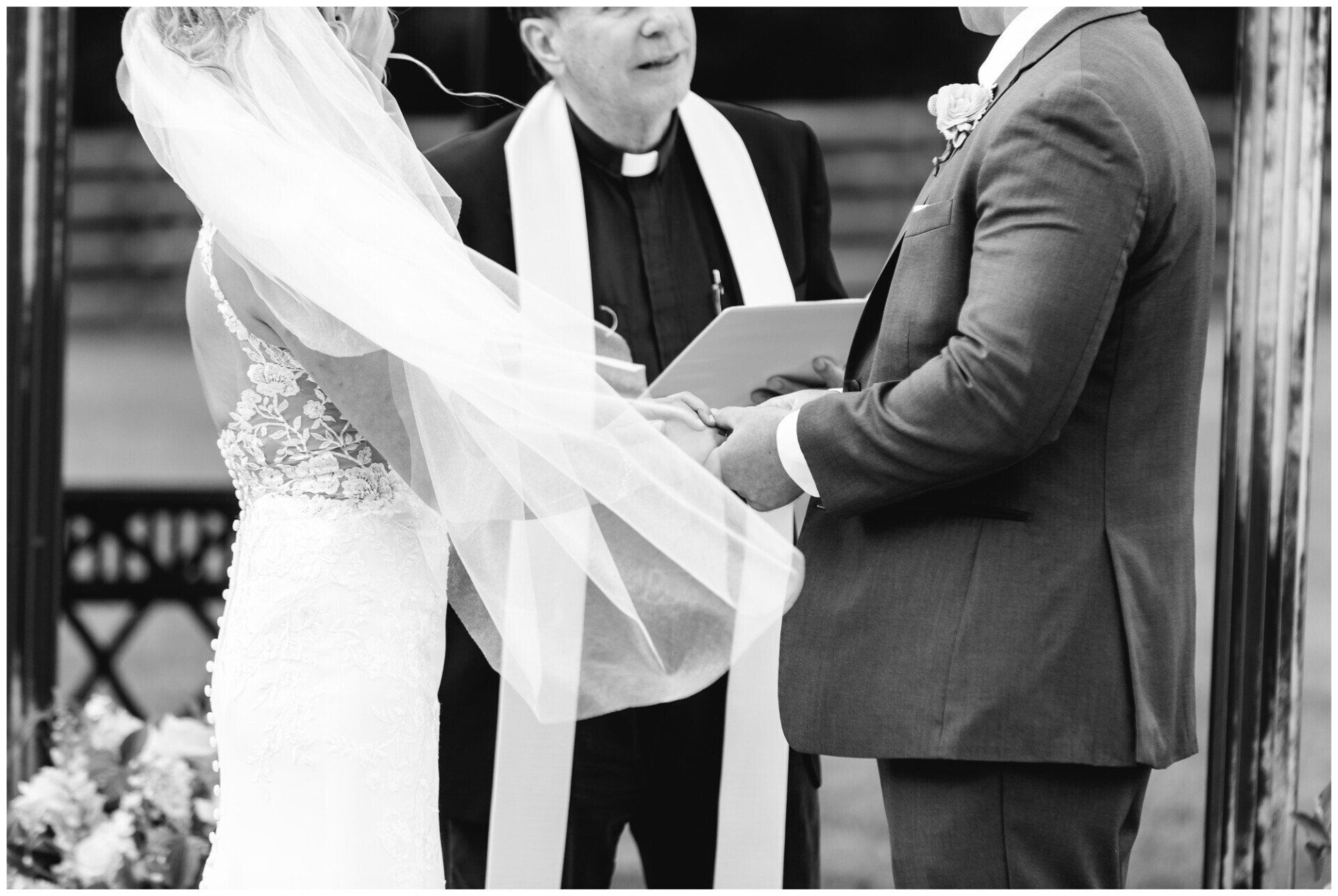 Bride and groom at altar with officiant, veil flowing across the foreground