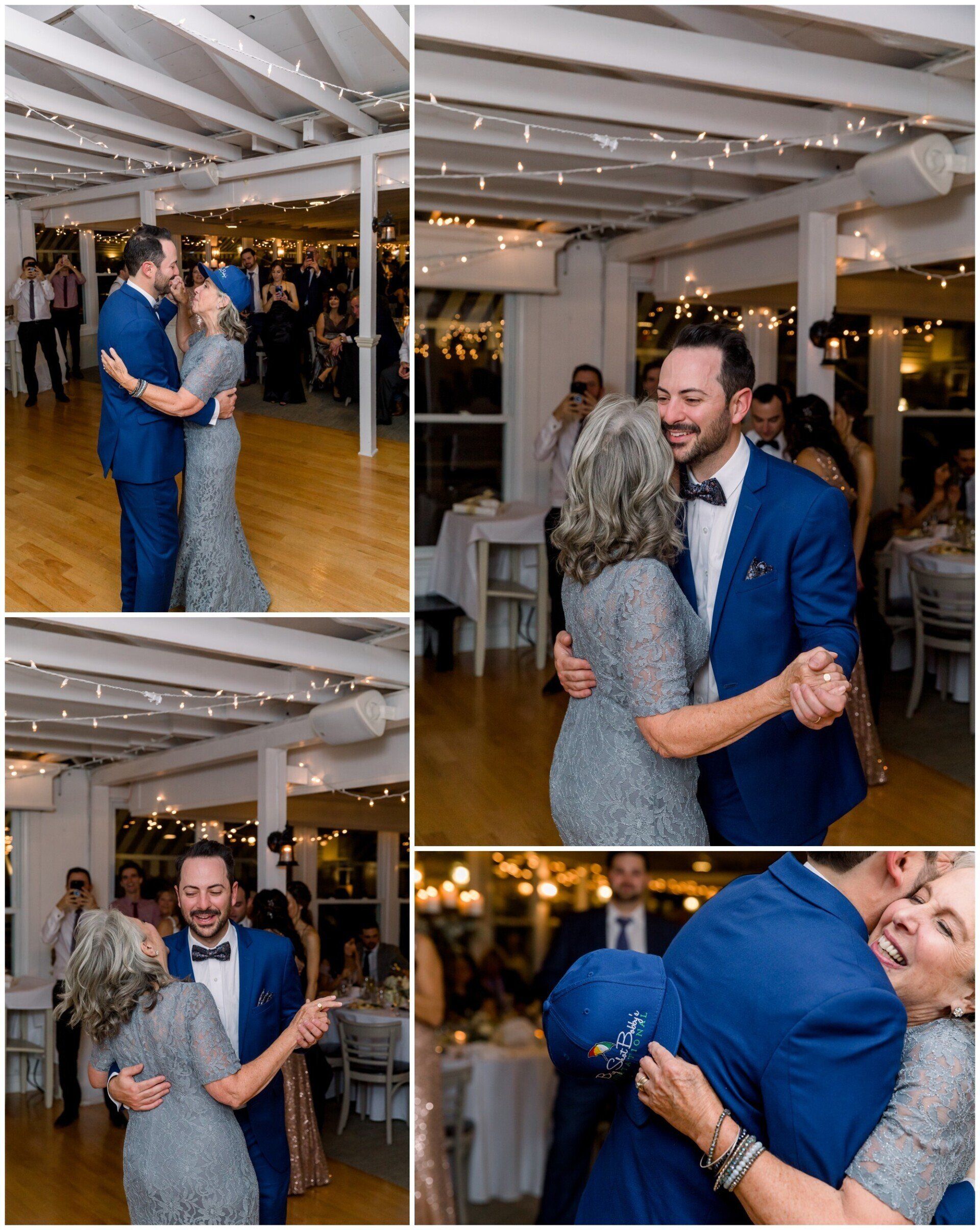 Guests dancing at a wedding reception in a white-beamed hall, with a smiling man in a blue suit in the foreground