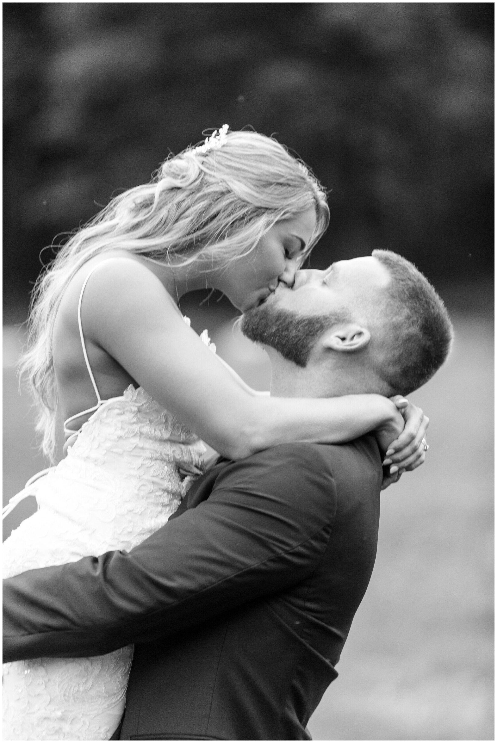 Couple embracing and kissing outdoors, with the woman leaning into the man in a grassy setting.