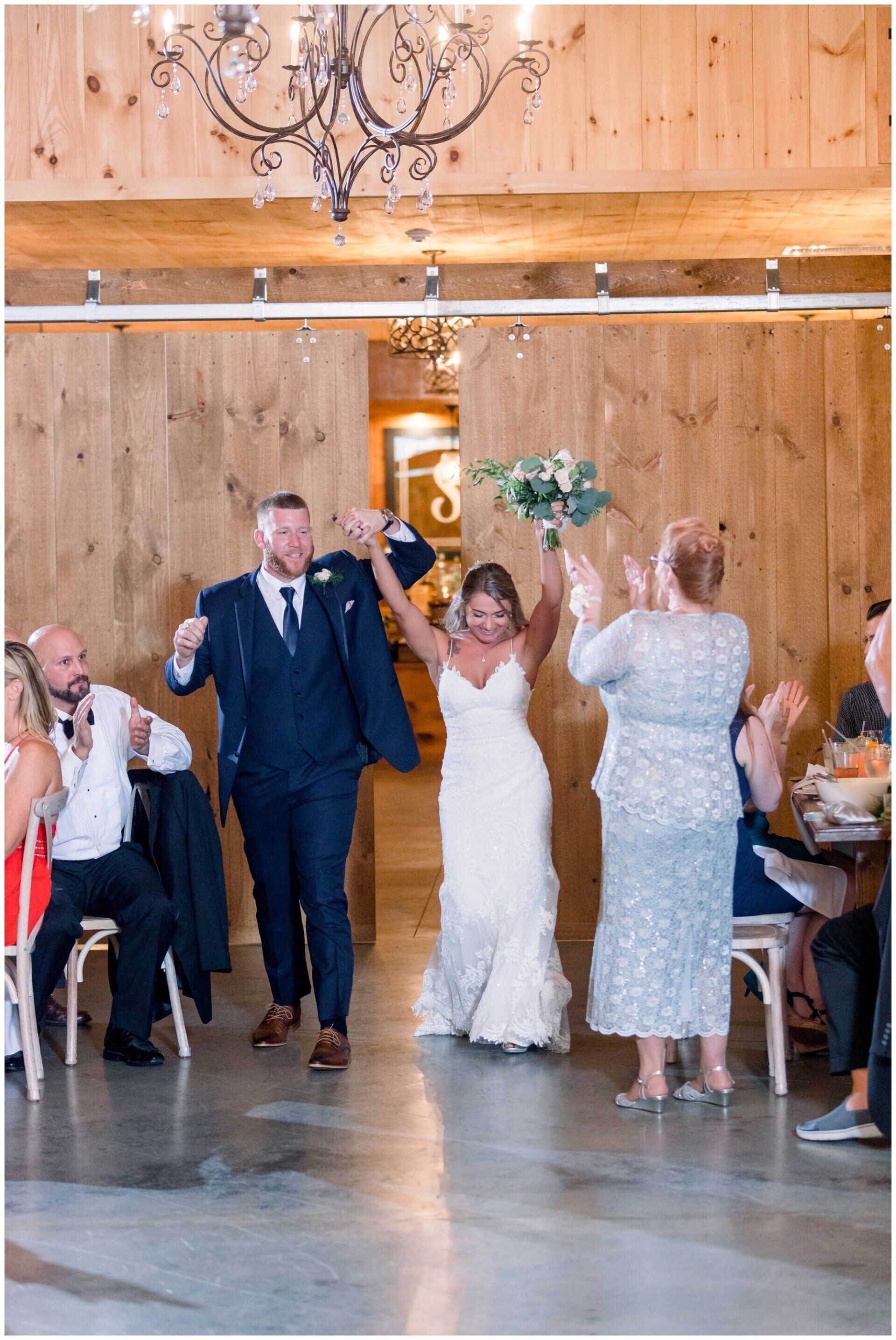 Wedding reception with couple dancing under a wooden chandelier in a barn-like venue