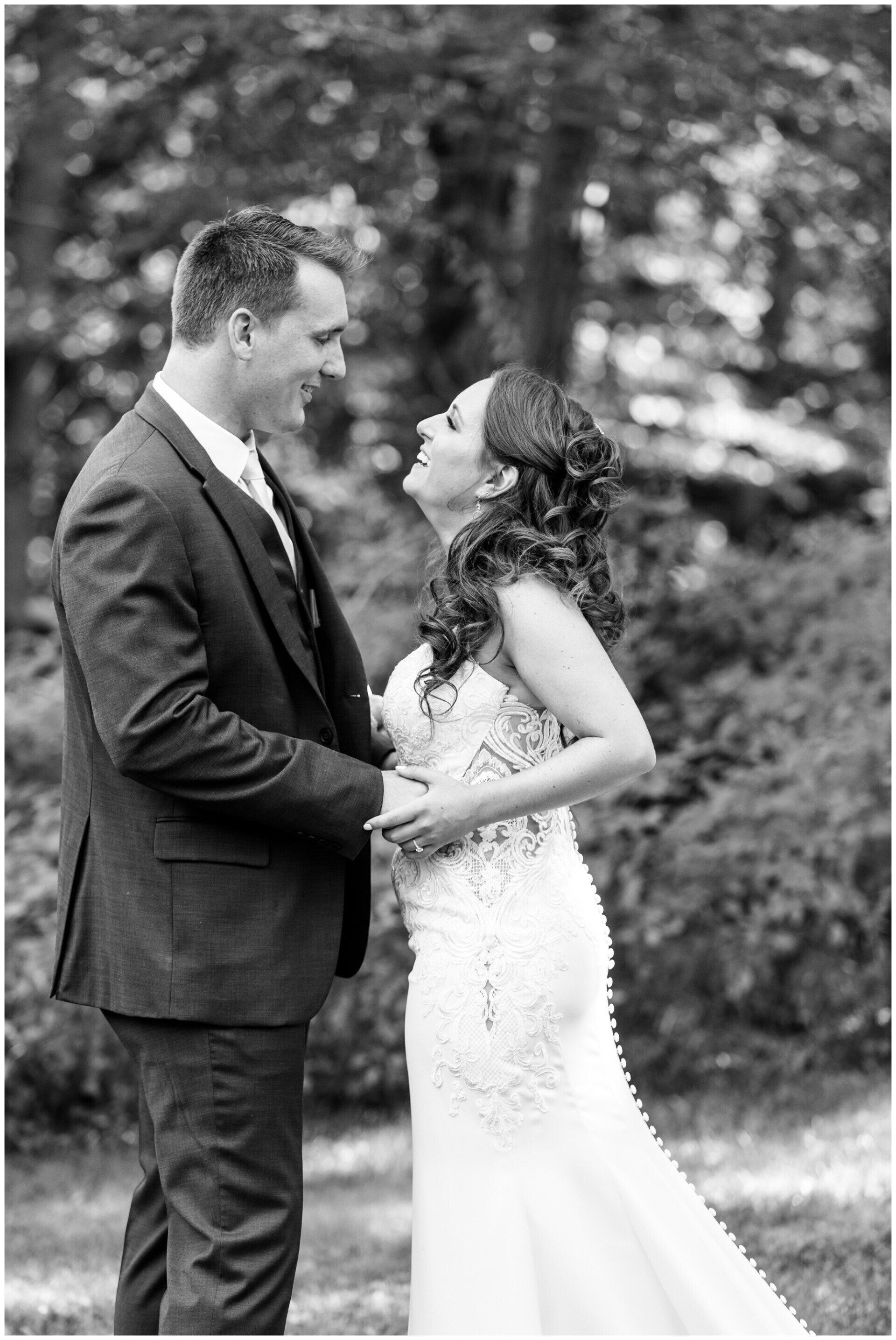 Bride and groom holding hands and smiling outdoors in a garden-like setting