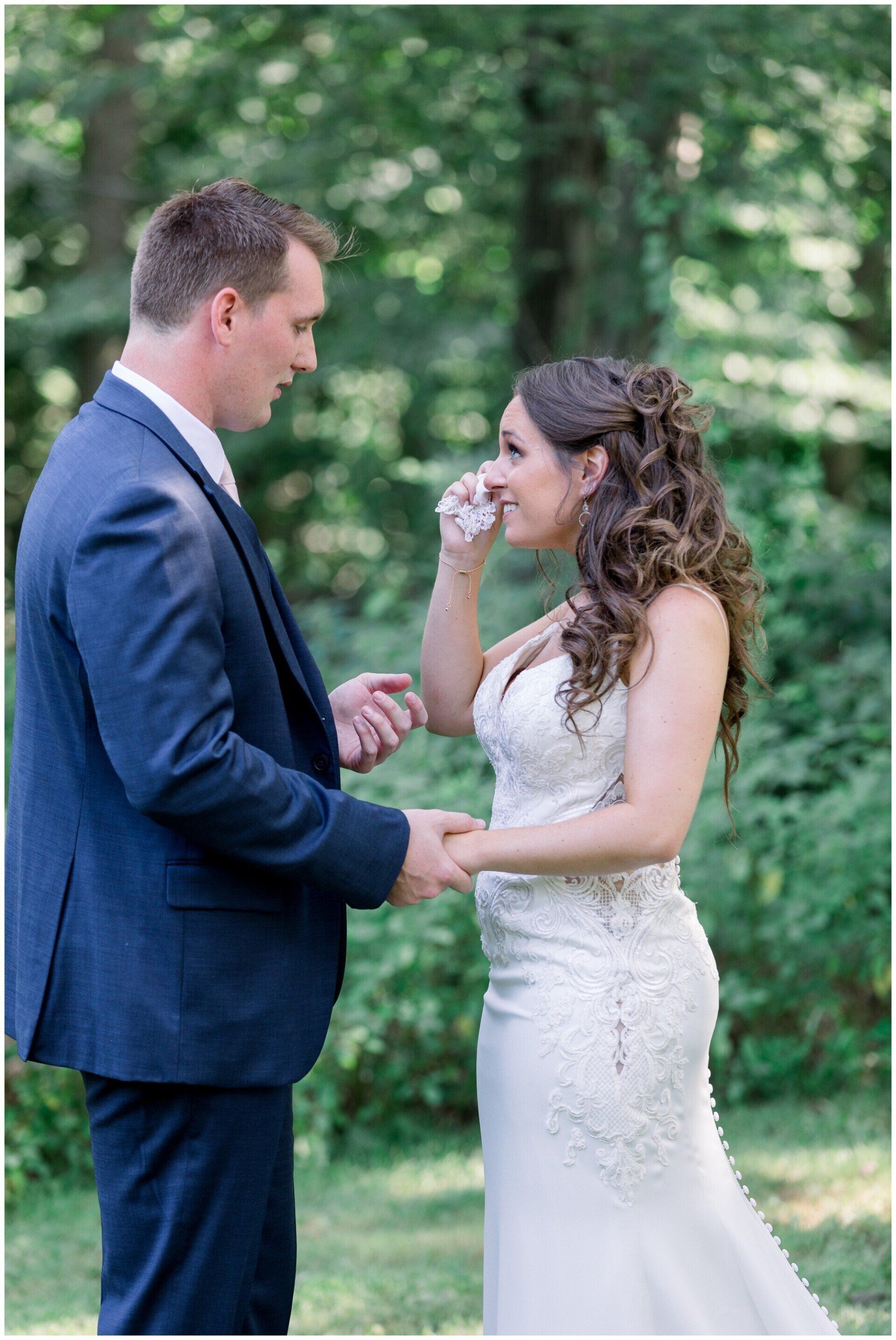 Bride and groom facing each other outdoors, holding hands during a wedding ceremony.
