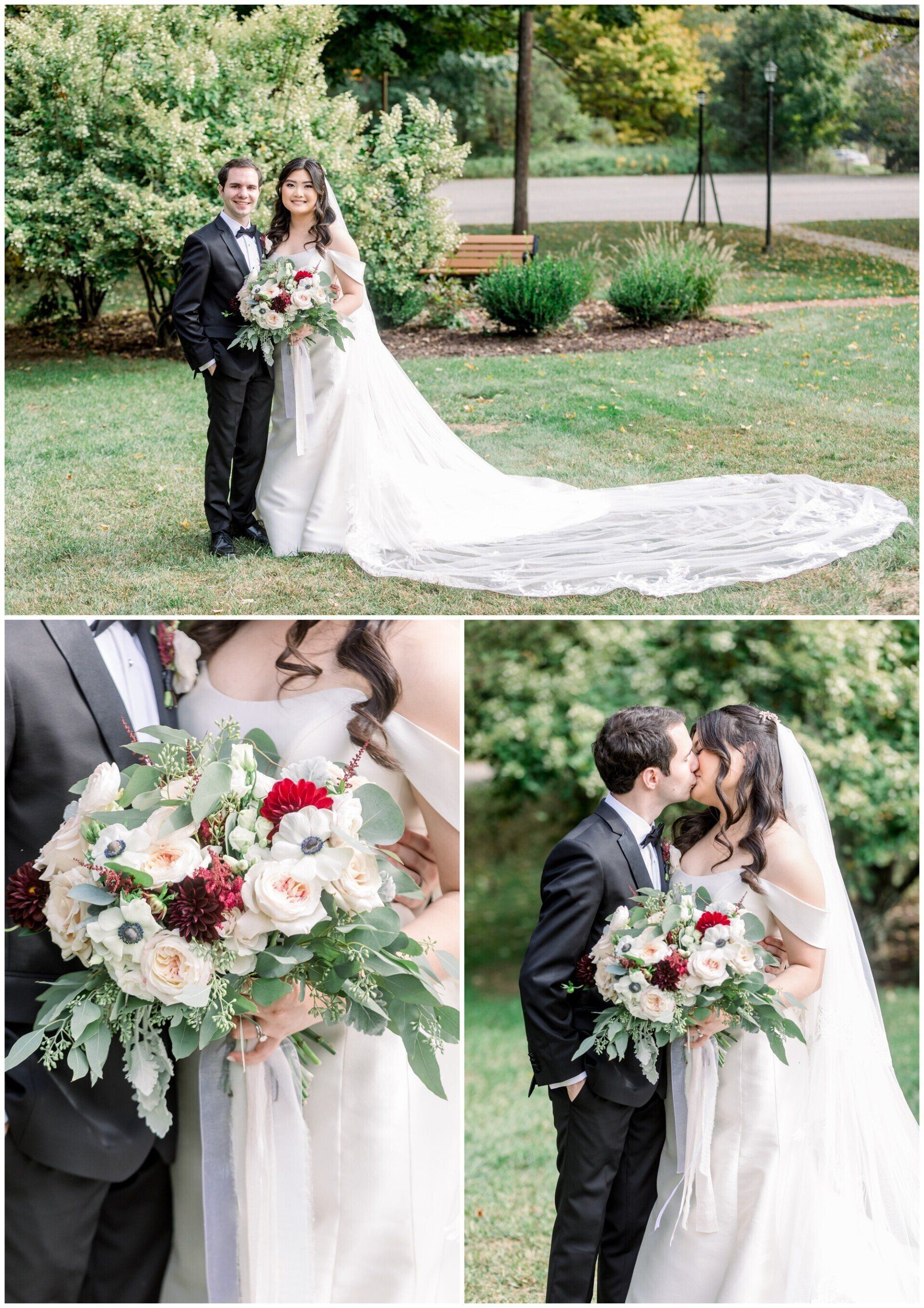 Wedding couple posing outdoors; bride holds pastel bouquet, groom in black tuxedo, long lace train on grass.