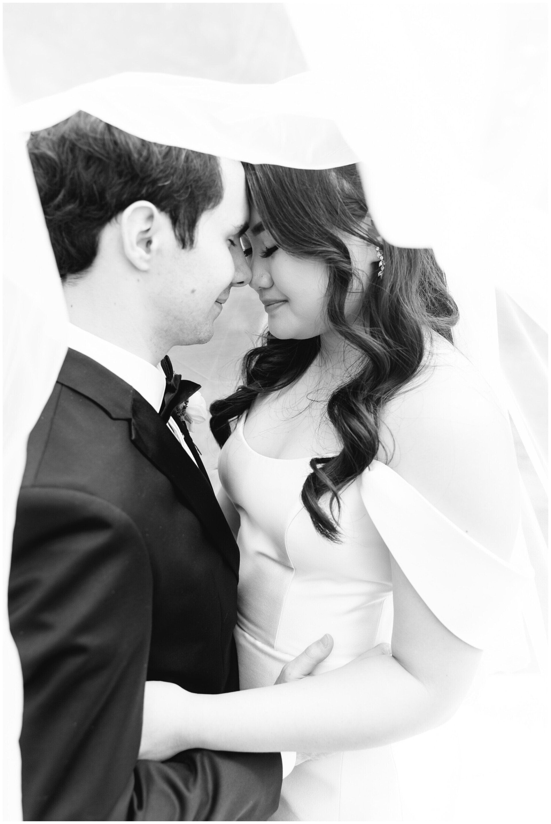 Black-and-white portrait of a couple in formal wear embracing and gazing at each other