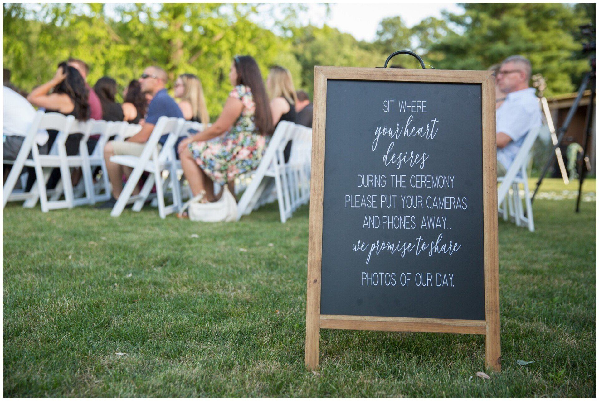 Outdoor wedding seating with a chalkboard sign on a grassy lawn