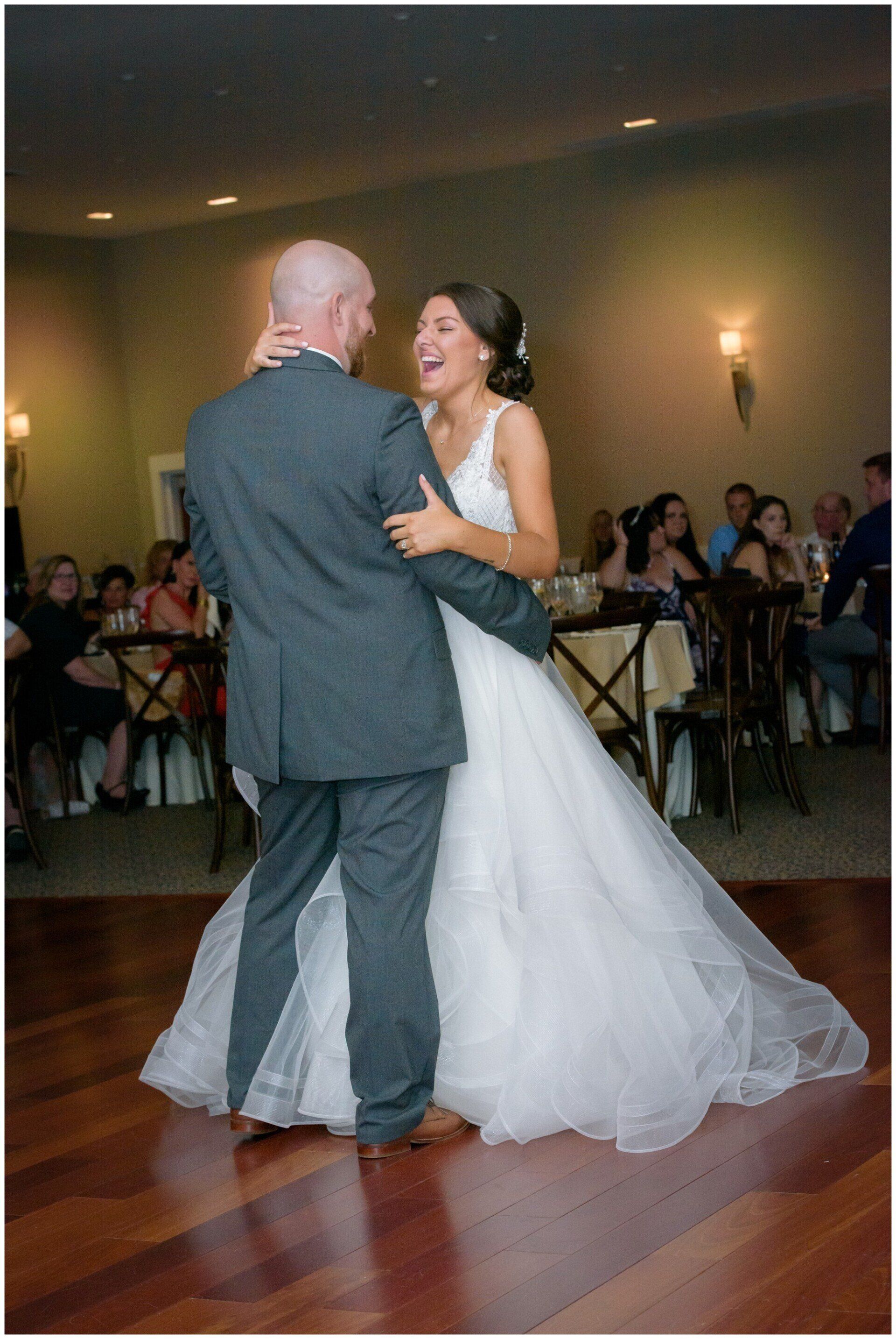 Bride and groom dancing at a wedding reception in a softly lit banquet hall