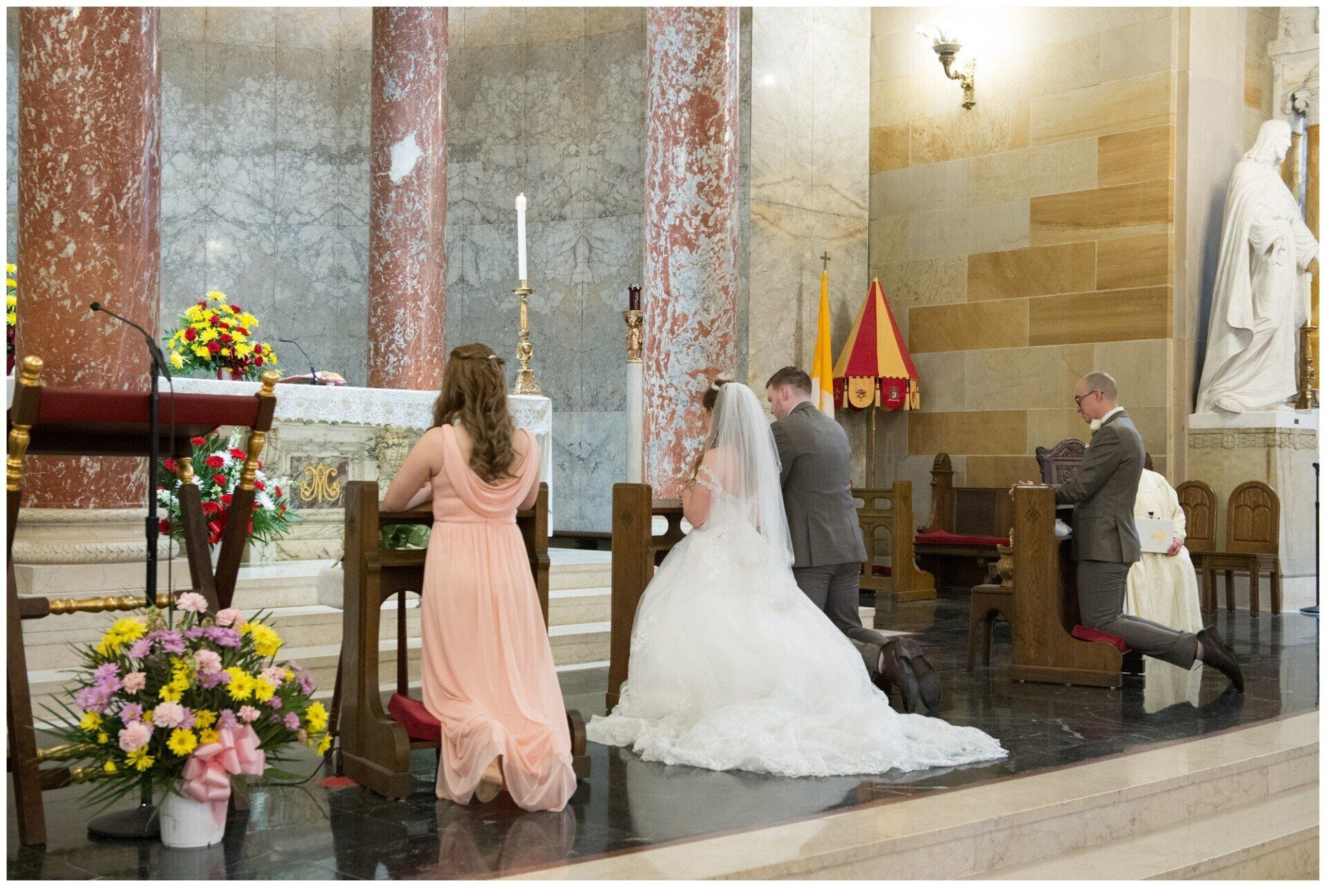 Wedding ceremony in a church, with bride and groom standing at the altar beside attendants.