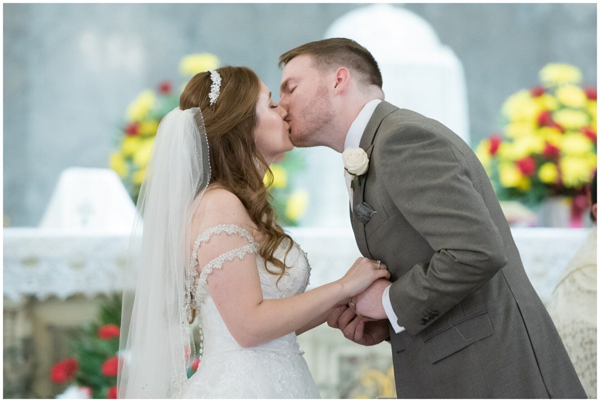 Bride and groom kissing at a wedding ceremony with colorful floral decor