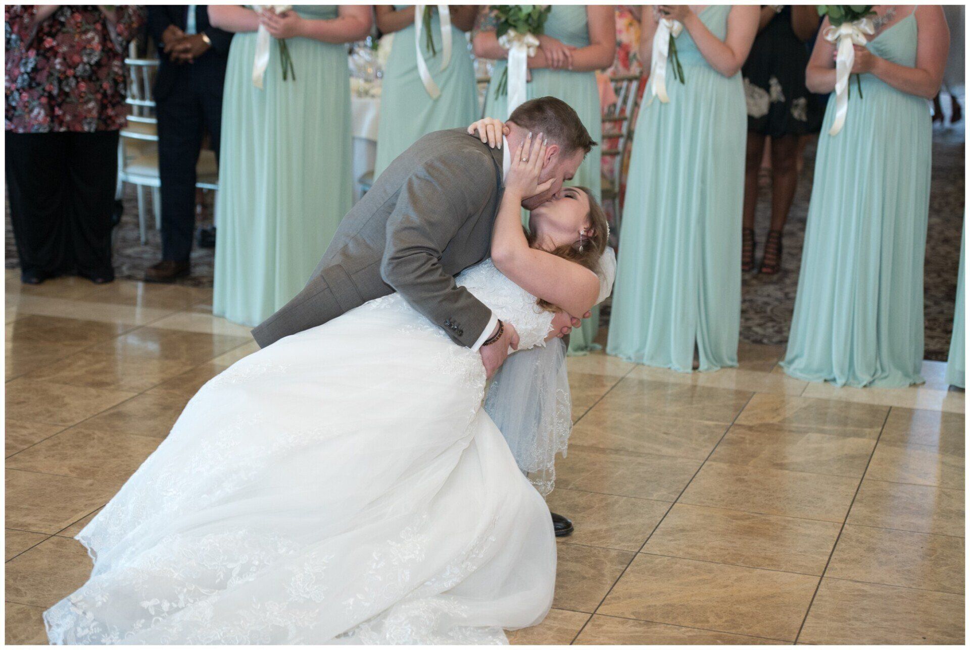Bride and groom dip kiss during their first dance at a wedding reception