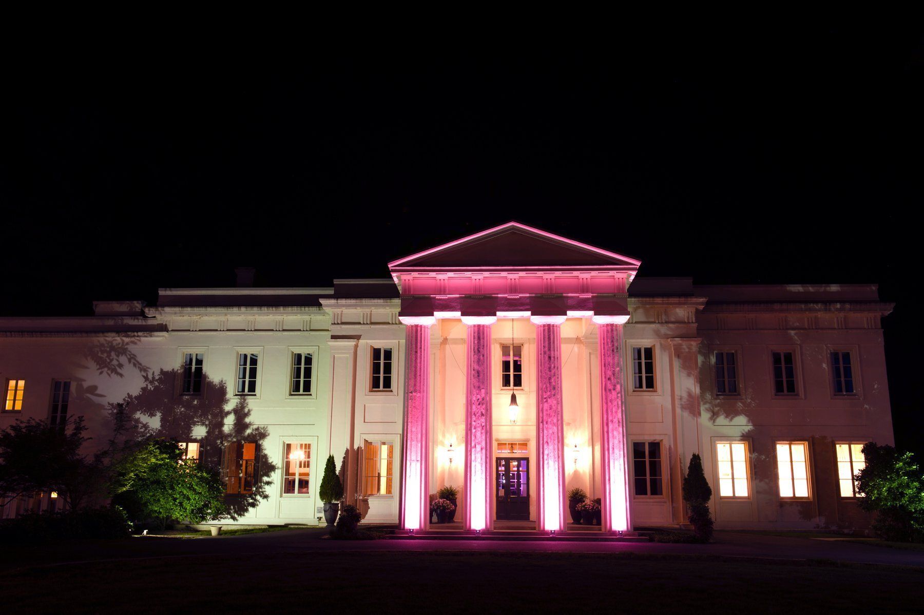 Illuminated neoclassical building at night, lit pink and white