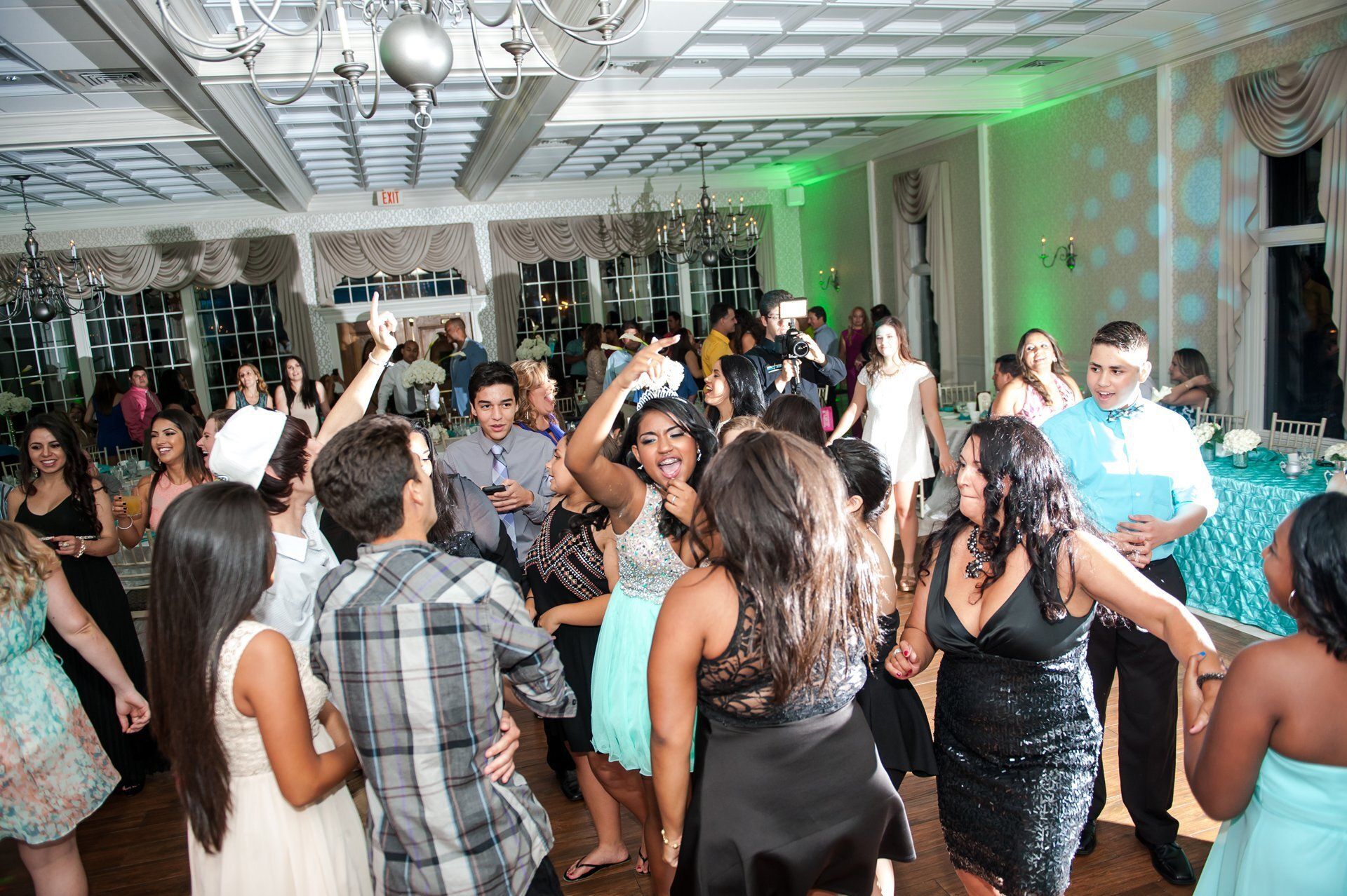 People dancing at a crowded indoor party with green and blue lighting