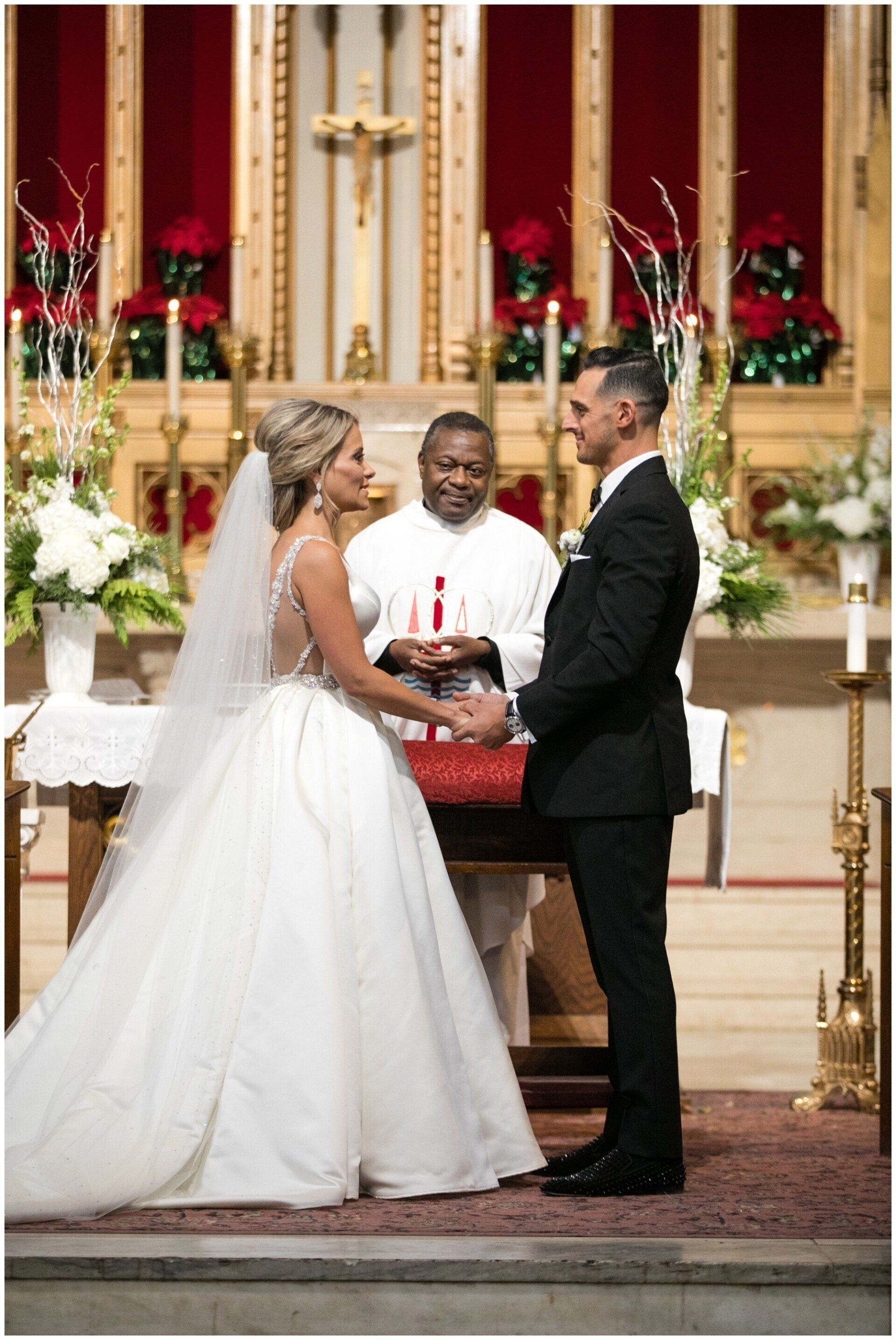 Bride and groom stand at the altar during a wedding ceremony in a decorated church.
