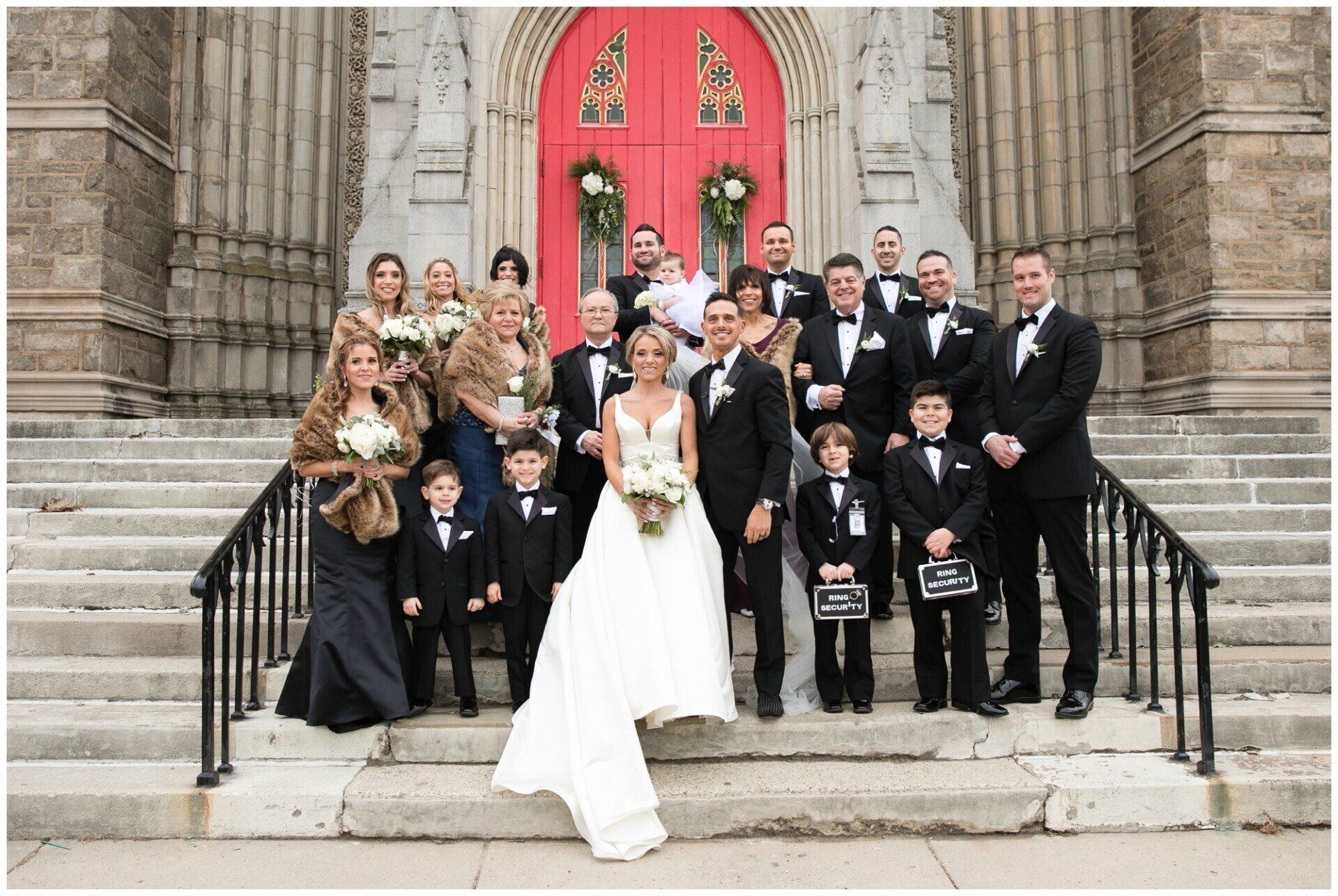 Wedding party posing on church steps in front of red double doors