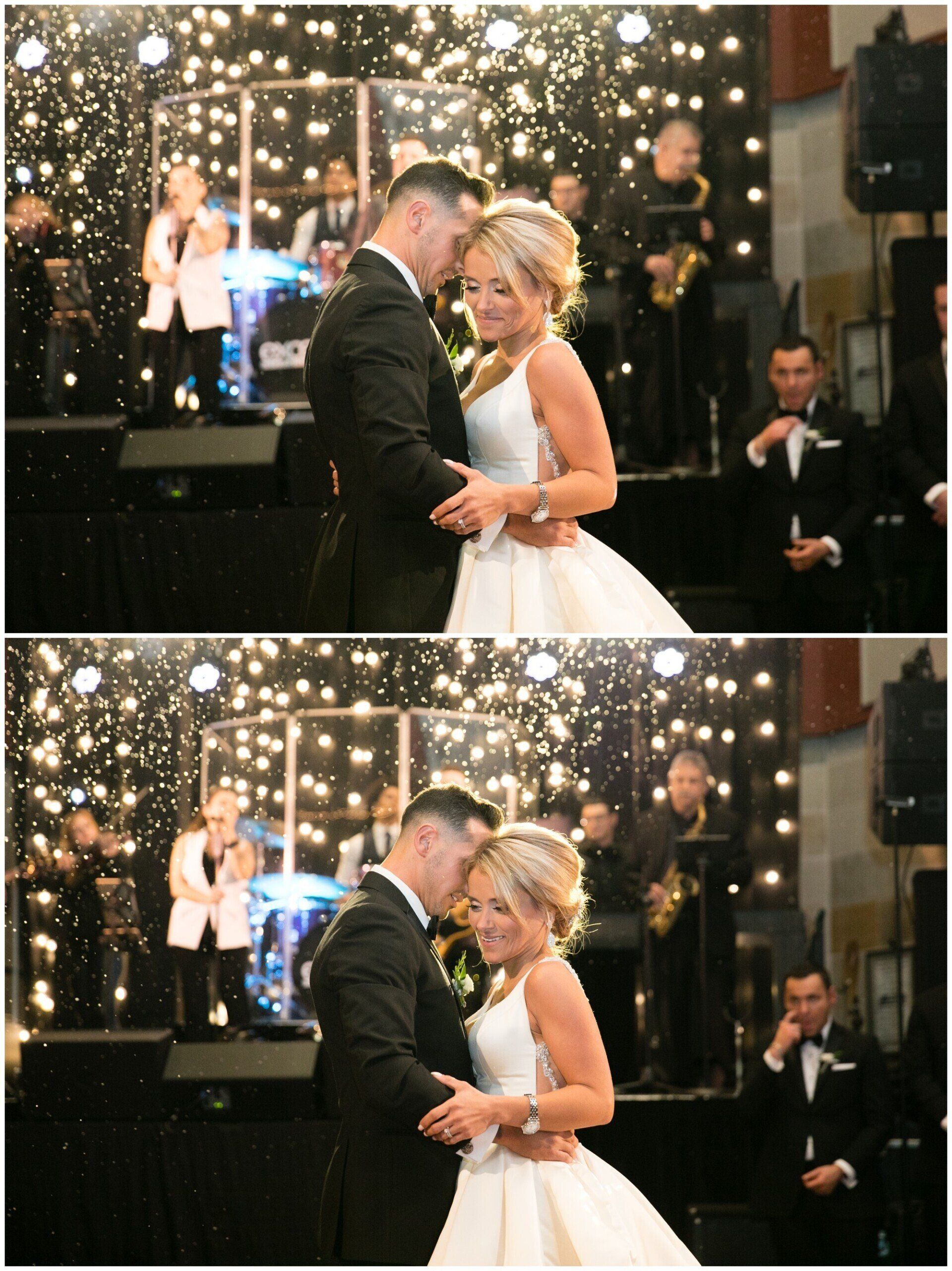 Bride and groom dance closely at a wedding reception with sparkling lights and guests watching.