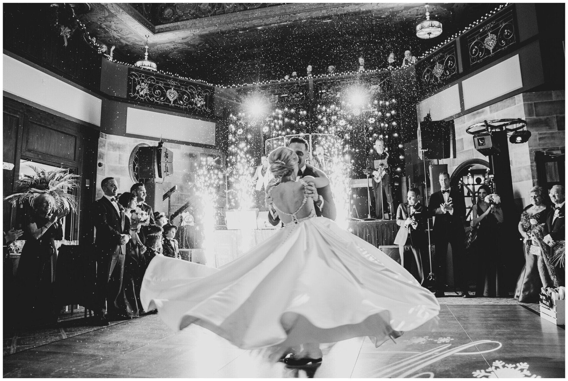 Bride in a white gown dancing under sparklers at an indoor wedding reception