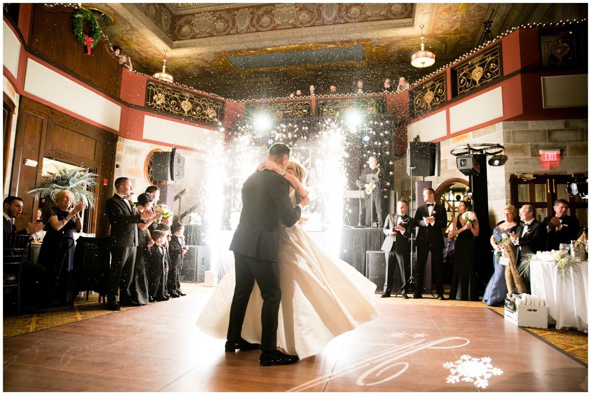 Bride and groom dancing in a decorated ballroom with sparklers and guests watching