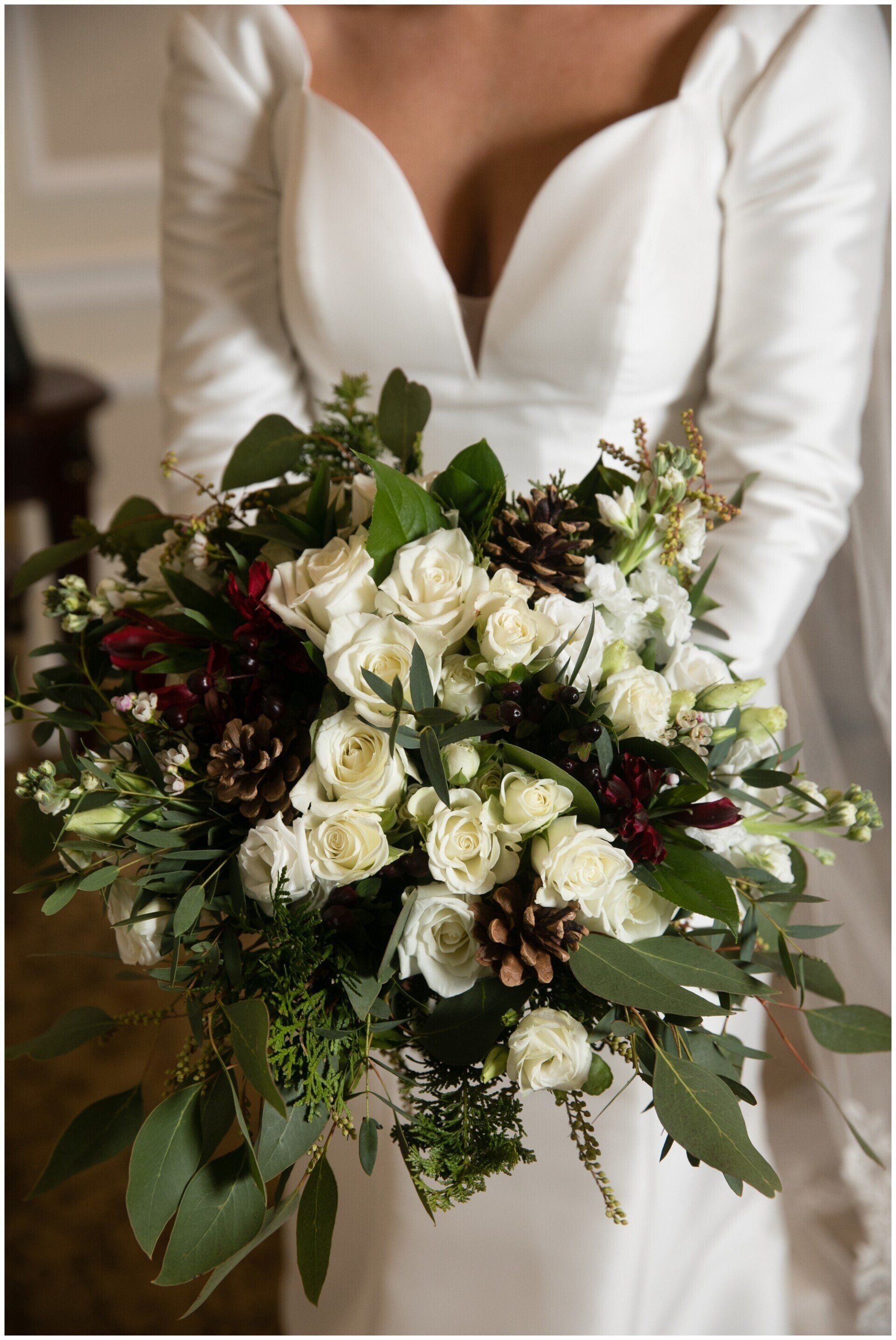 Bride holding a large white and burgundy floral bouquet in a white dress