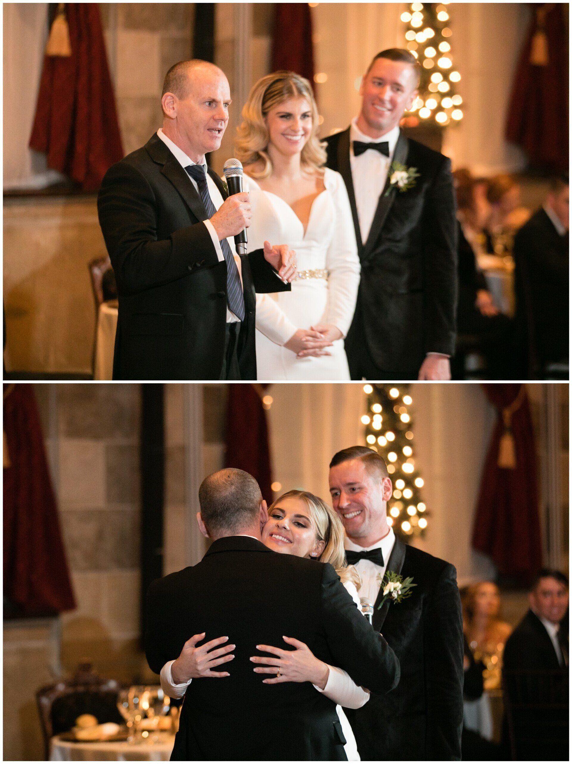 Wedding toast and embrace between groom, bride in white, and speaker in tuxedo at a warmly lit reception.