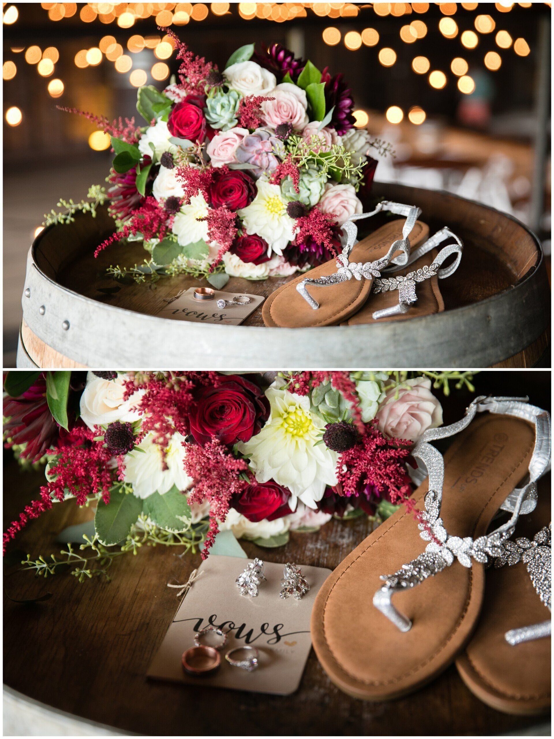 Wedding bouquet, rings, and silver sandals on a wooden barrel with warm lights in the background