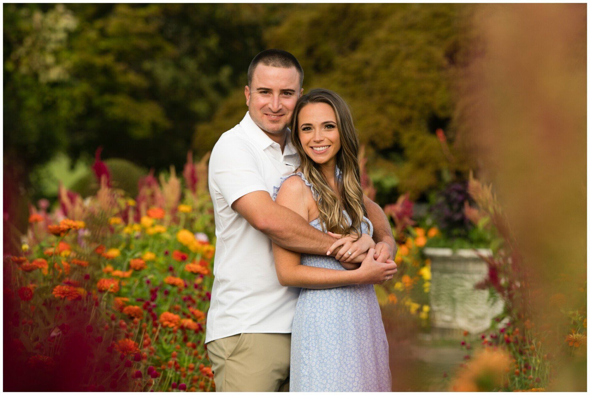 Couple embracing in a colorful flower garden, smiling at the camera.