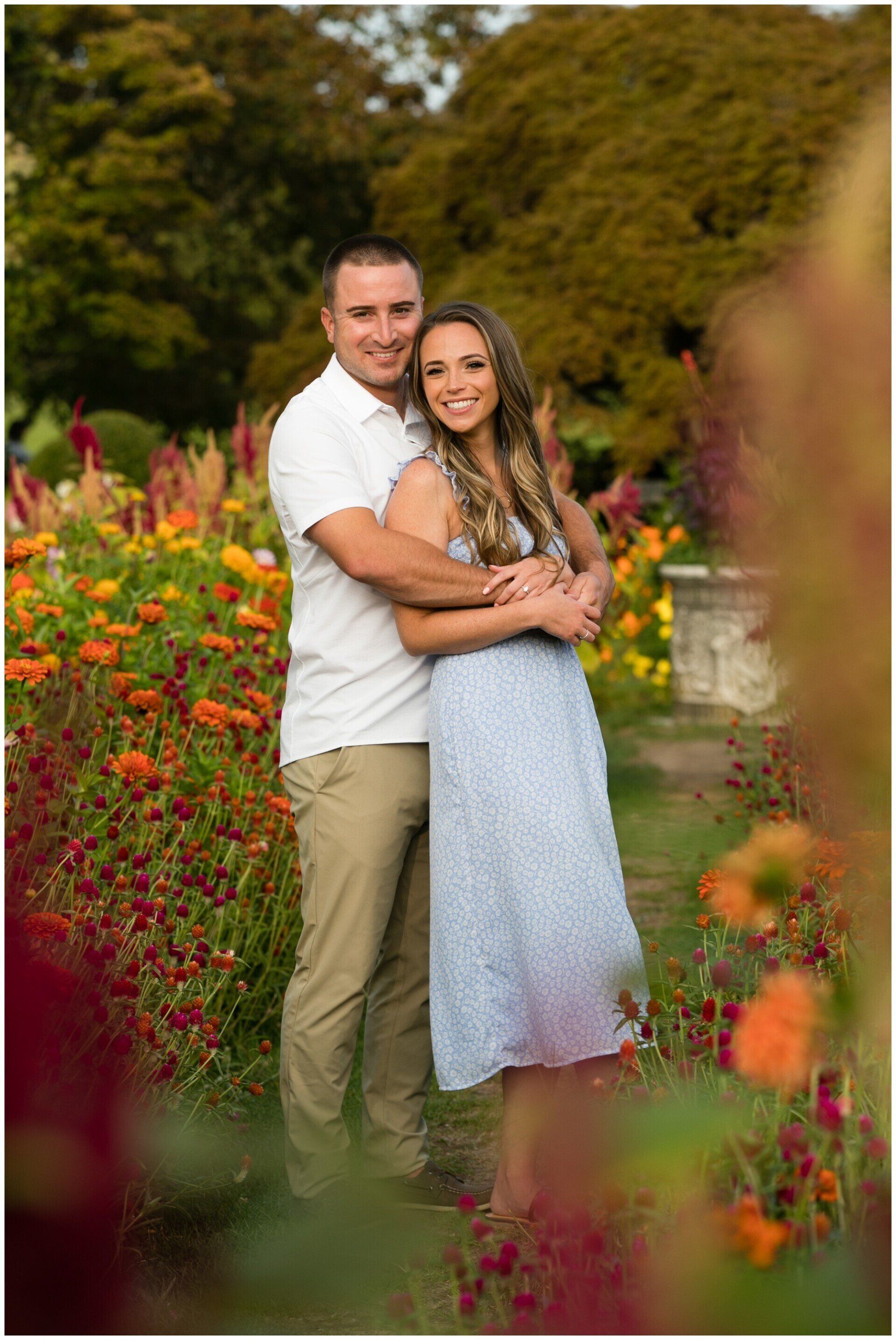 Couple embracing in a flower garden, surrounded by colorful blooms and greenery.