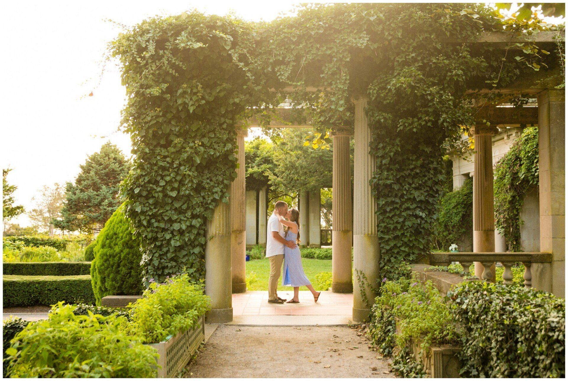 Person walking through a vine-covered garden archway in a sunlit park