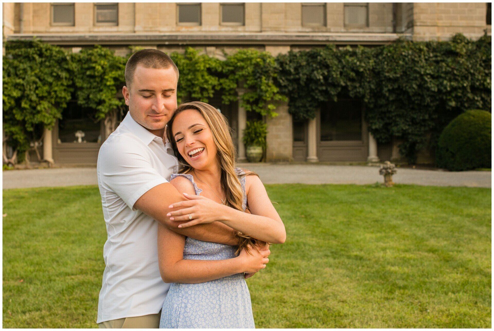 Couple embracing on a green lawn in front of a building, smiling warmly