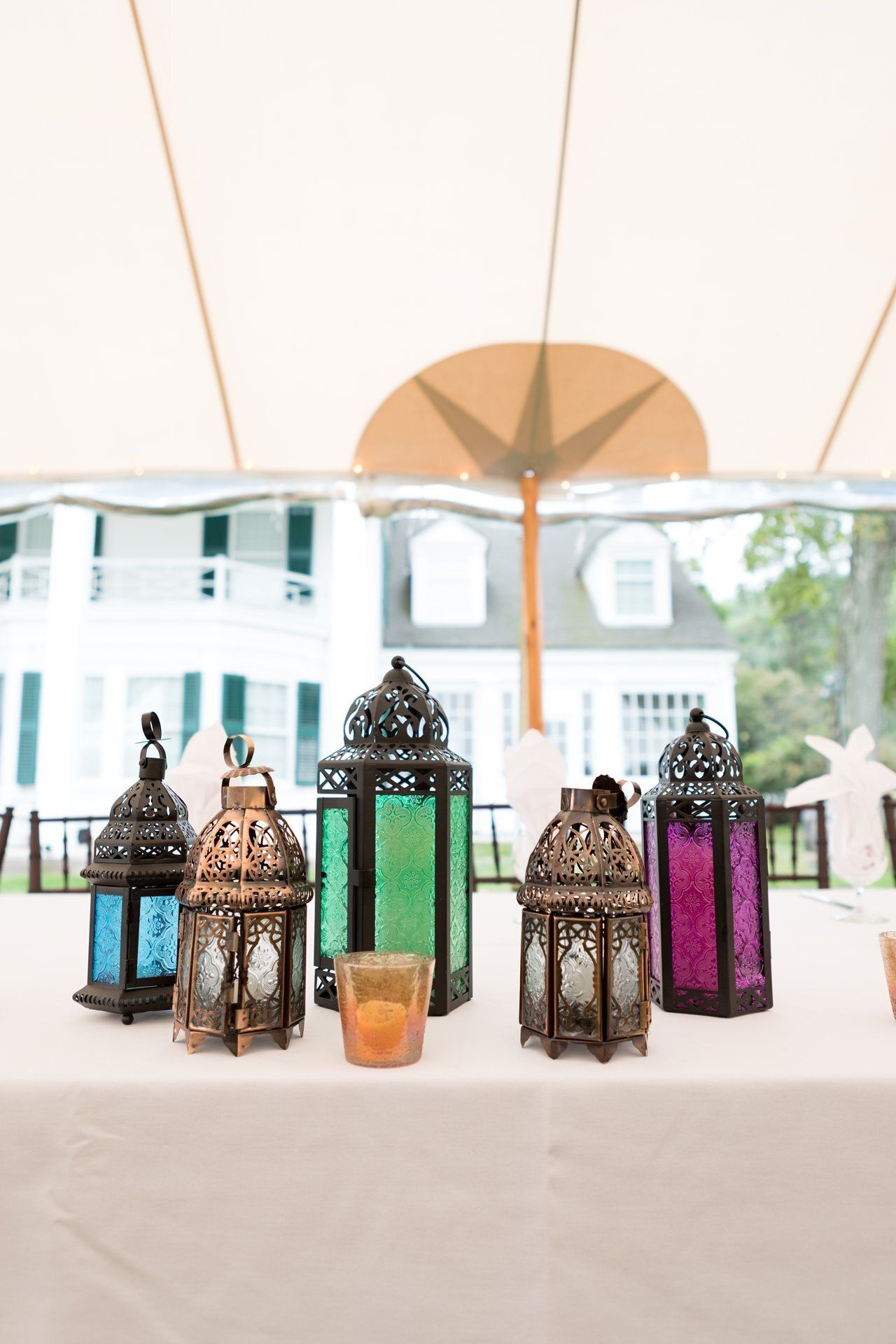 Colorful decorative lanterns on a white table under a tent at an outdoor event