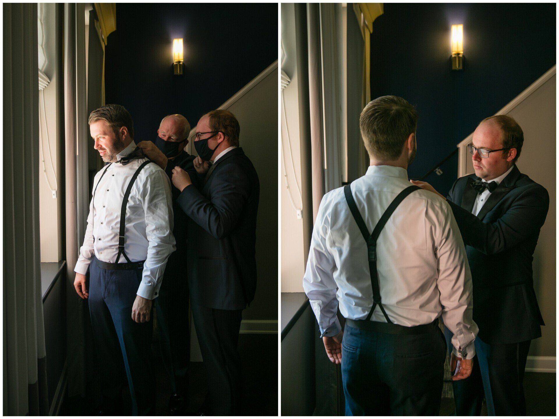 Two men adjusting a suit on a man in suspenders beside a staircase in a dim hallway