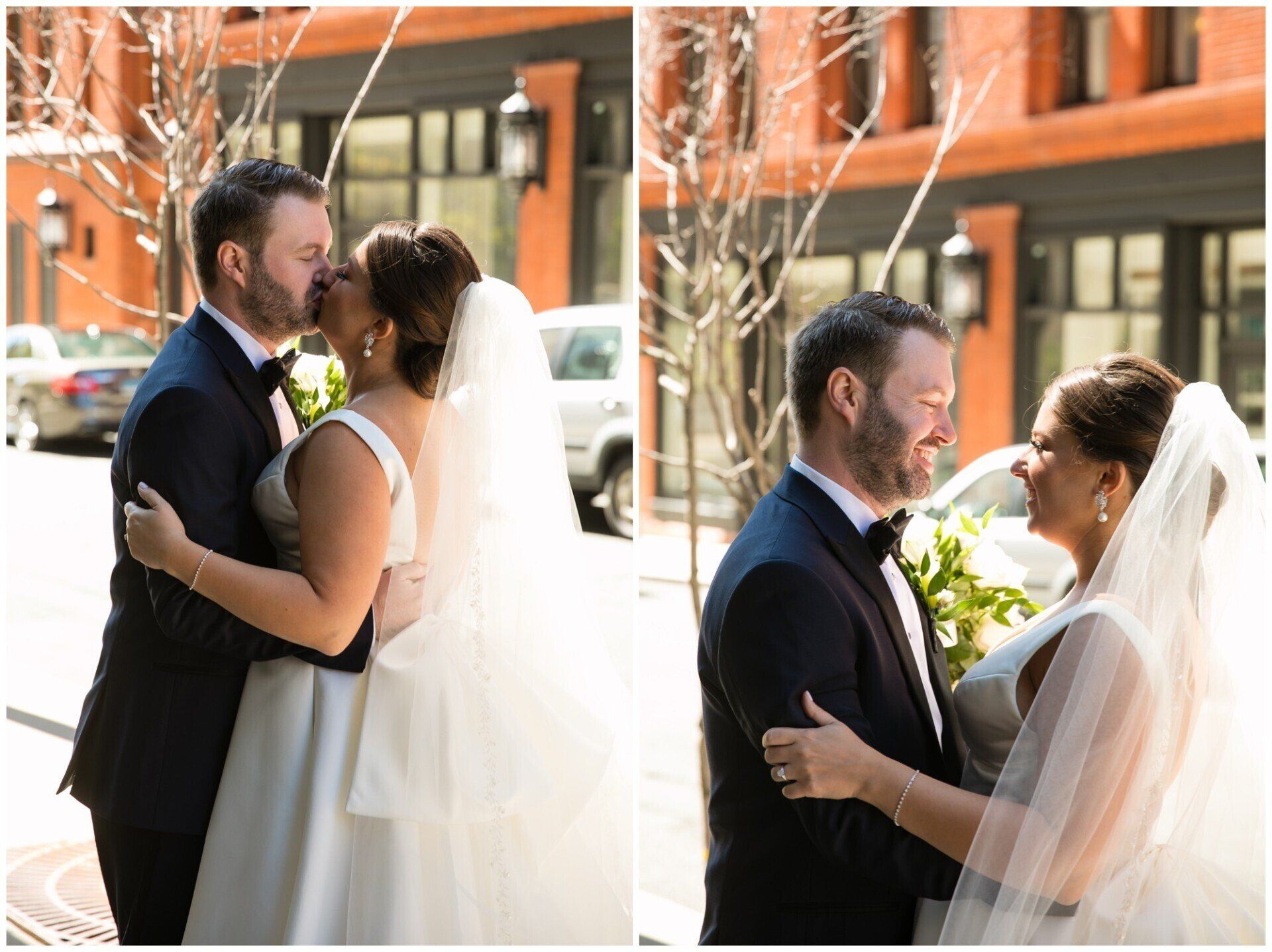 Wedding couple embracing outdoors in front of a brick building, bride in white veil and groom in a dark suit