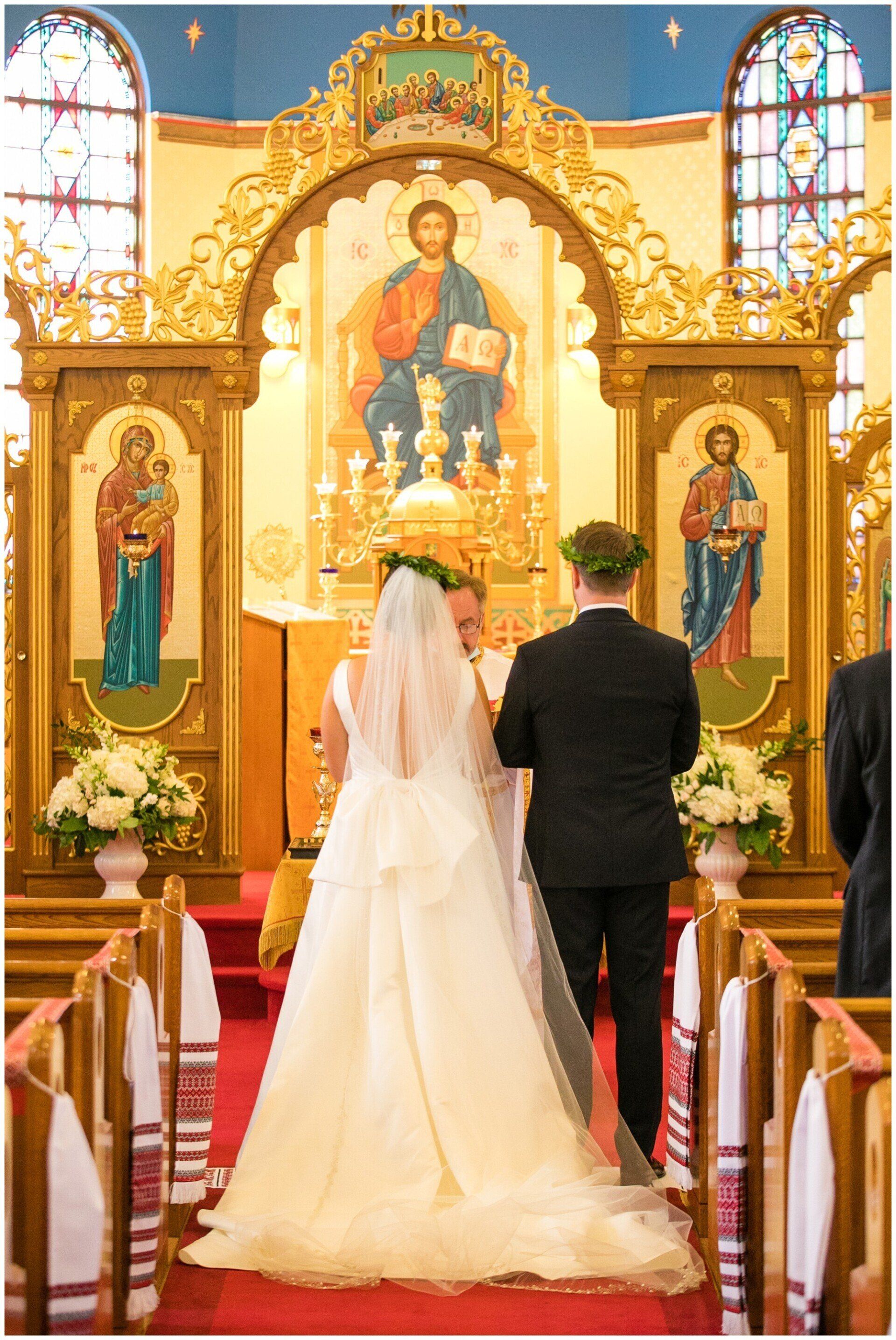 Bride and groom standing at church altar before ornate gold religious icon