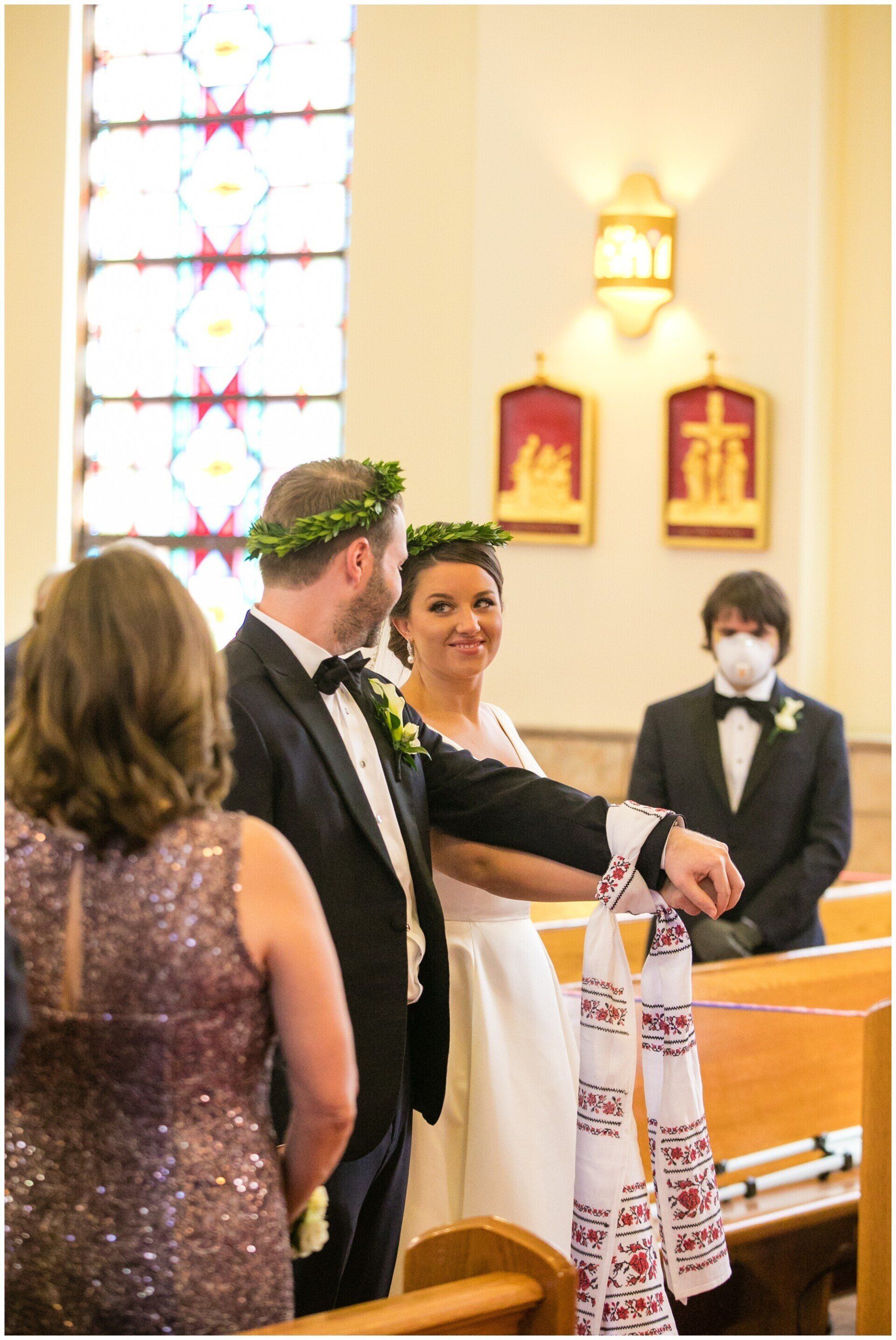 Bride and groom during a wedding ceremony, standing at the altar in a church with a priest nearby.