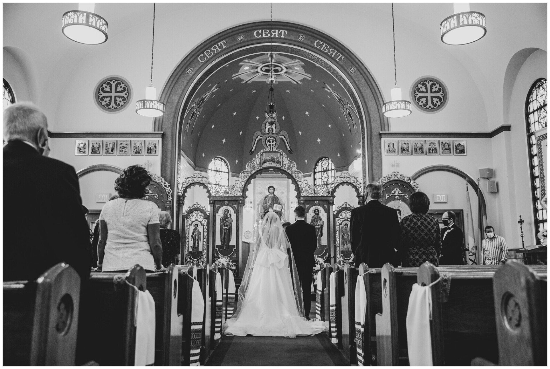 Wedding ceremony in a church, with bride and groom at the altar and guests seated in pews.
