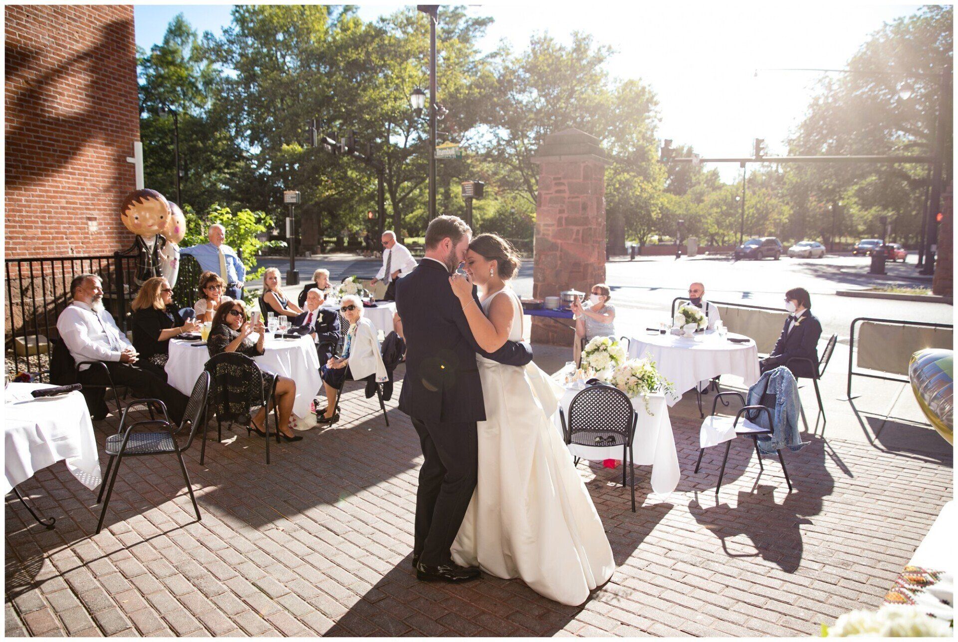 Bride and groom dancing at an outdoor wedding reception on a sunny patio
