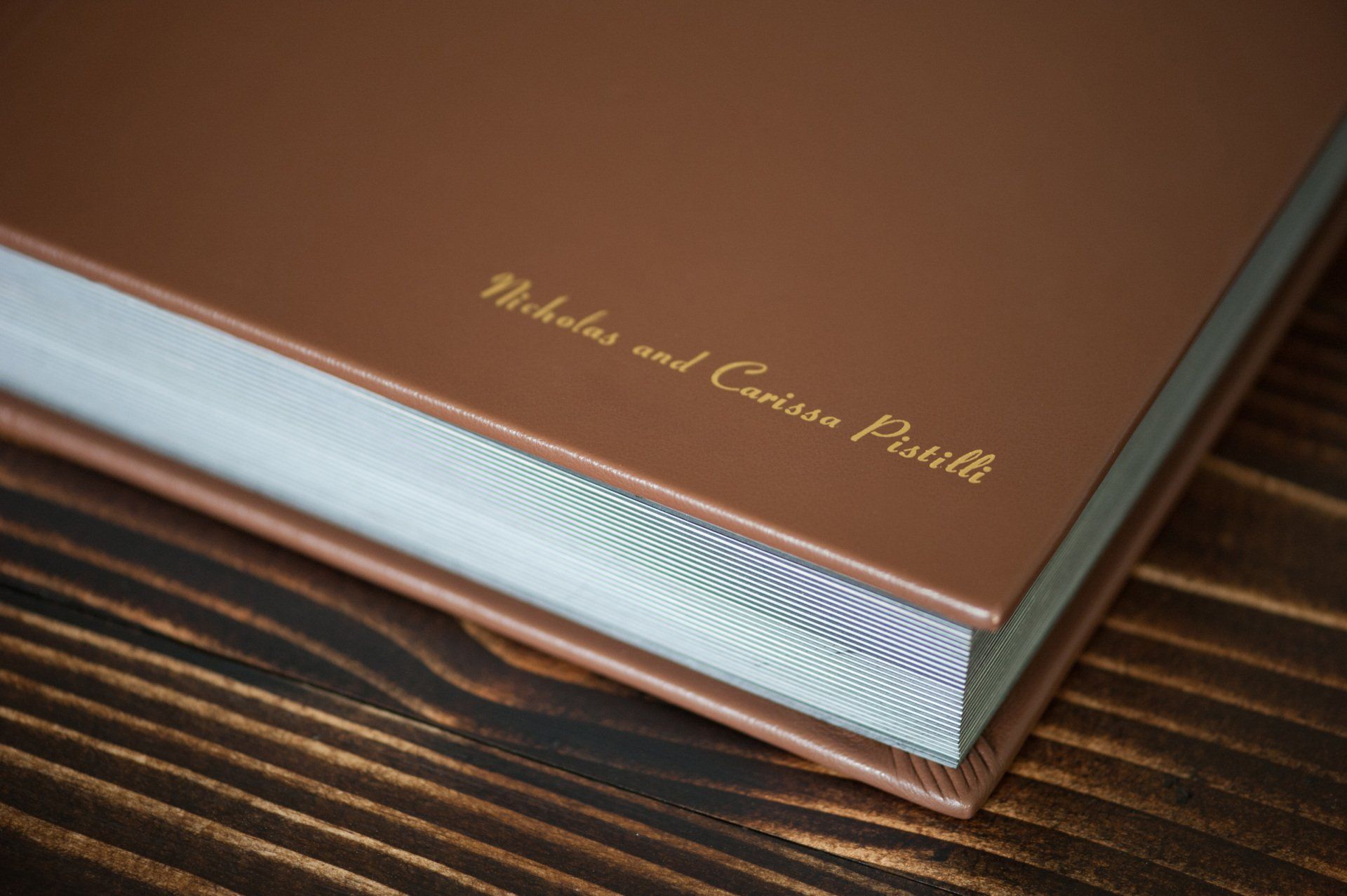 Brown and silver hardcover book on a wooden table, embossed with gold lettering